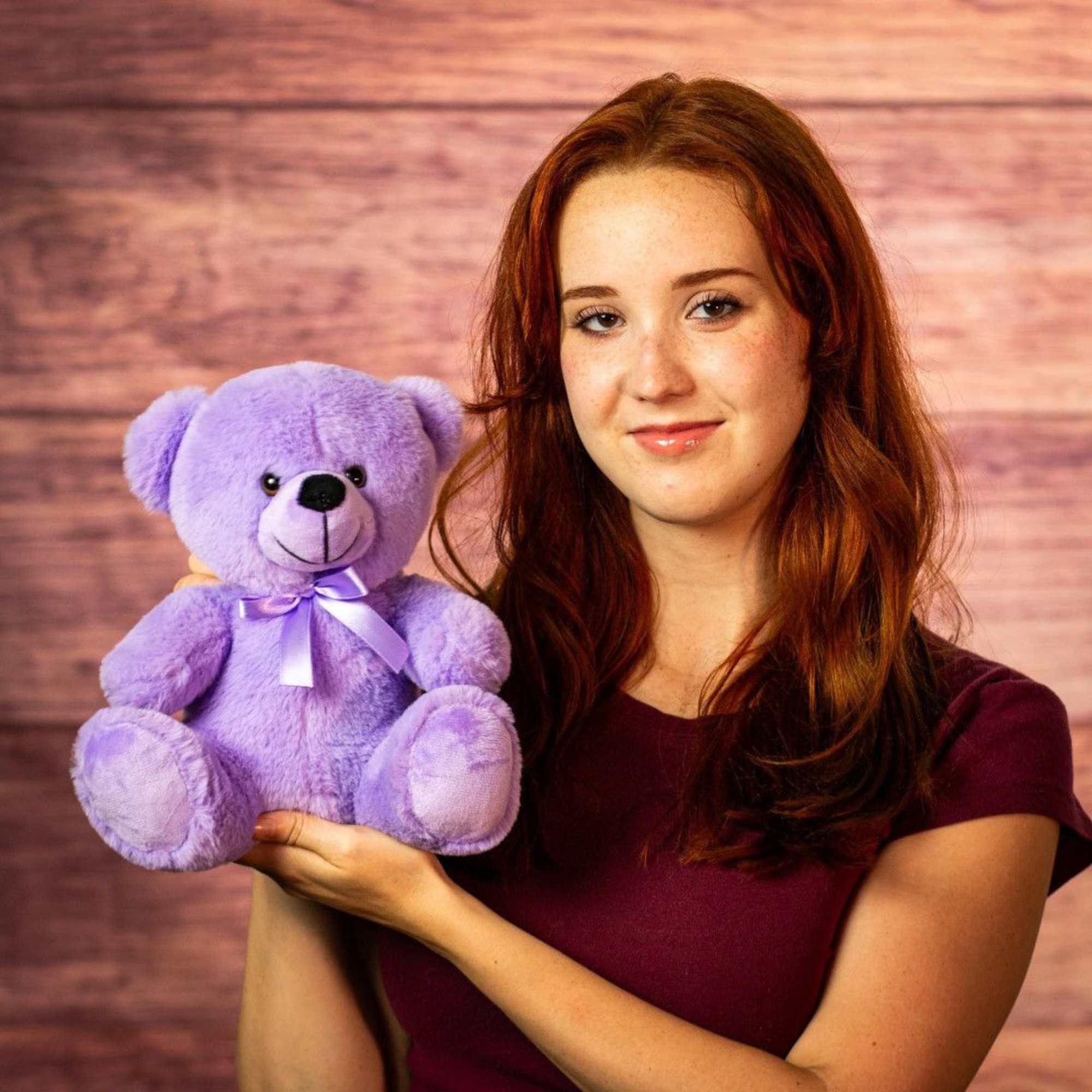 Woman holding a purple teddy bear with a ribbon