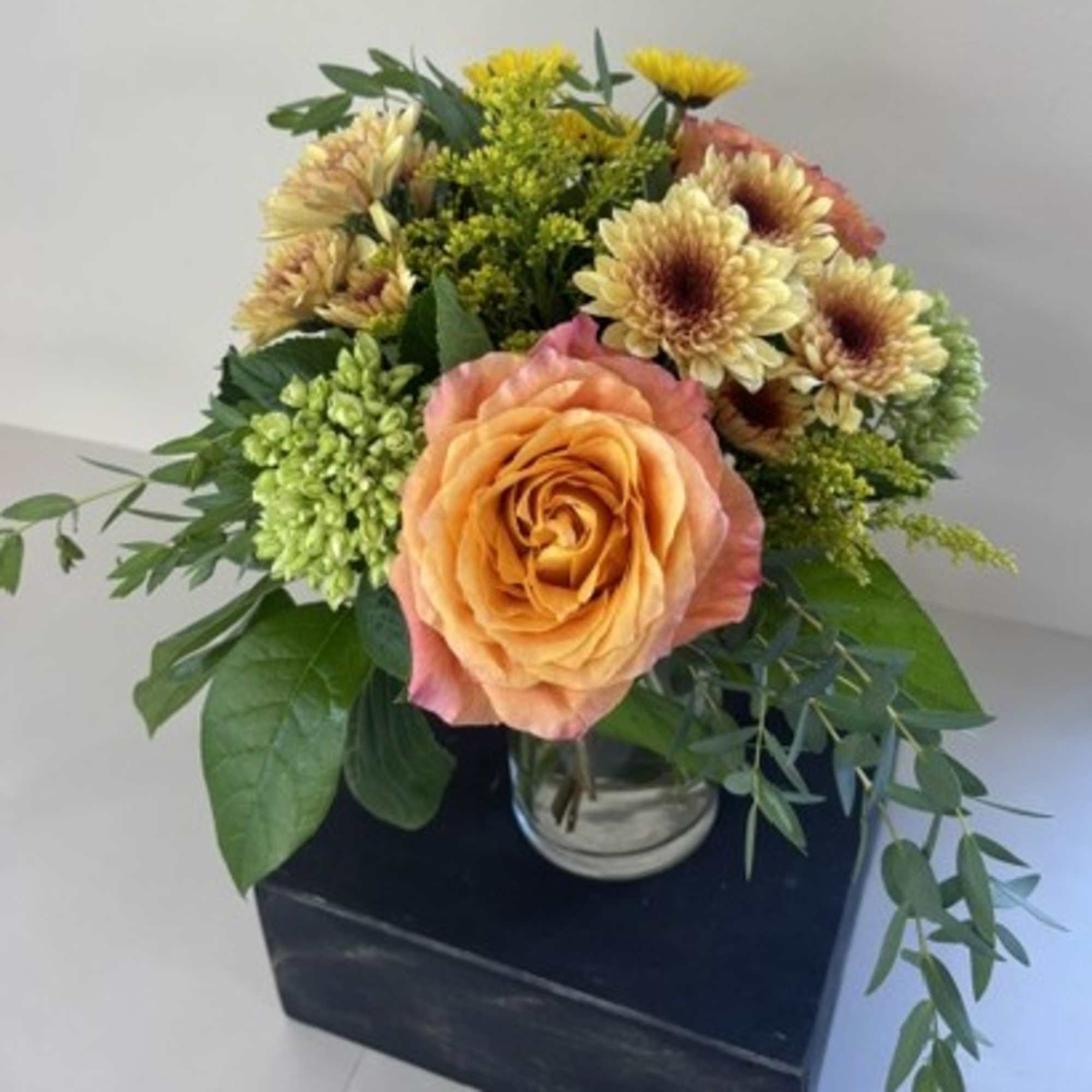 Peach rose bouquet with yellow chrysanthemums in a glass vase