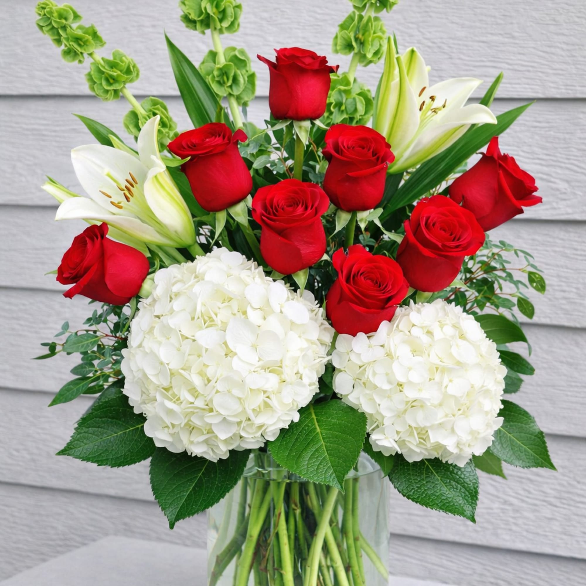 Red roses and white lilies with hydrangeas in a glass vase
