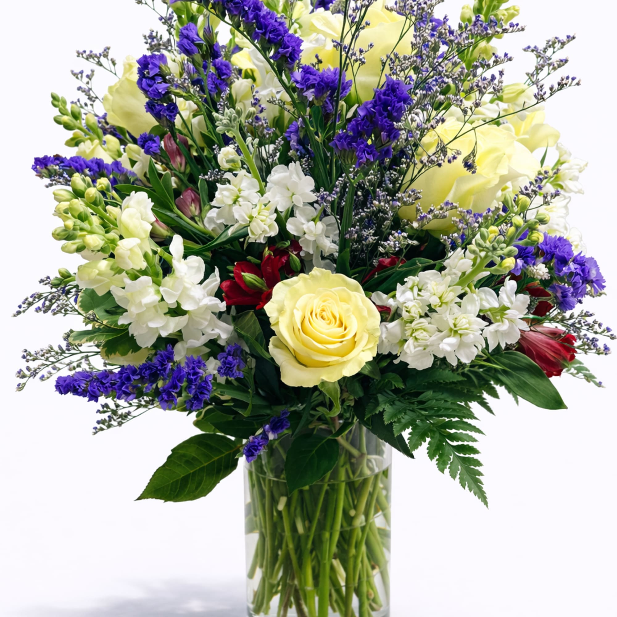 Mixed bouquet of yellow, white, and purple flowers in a glass vase