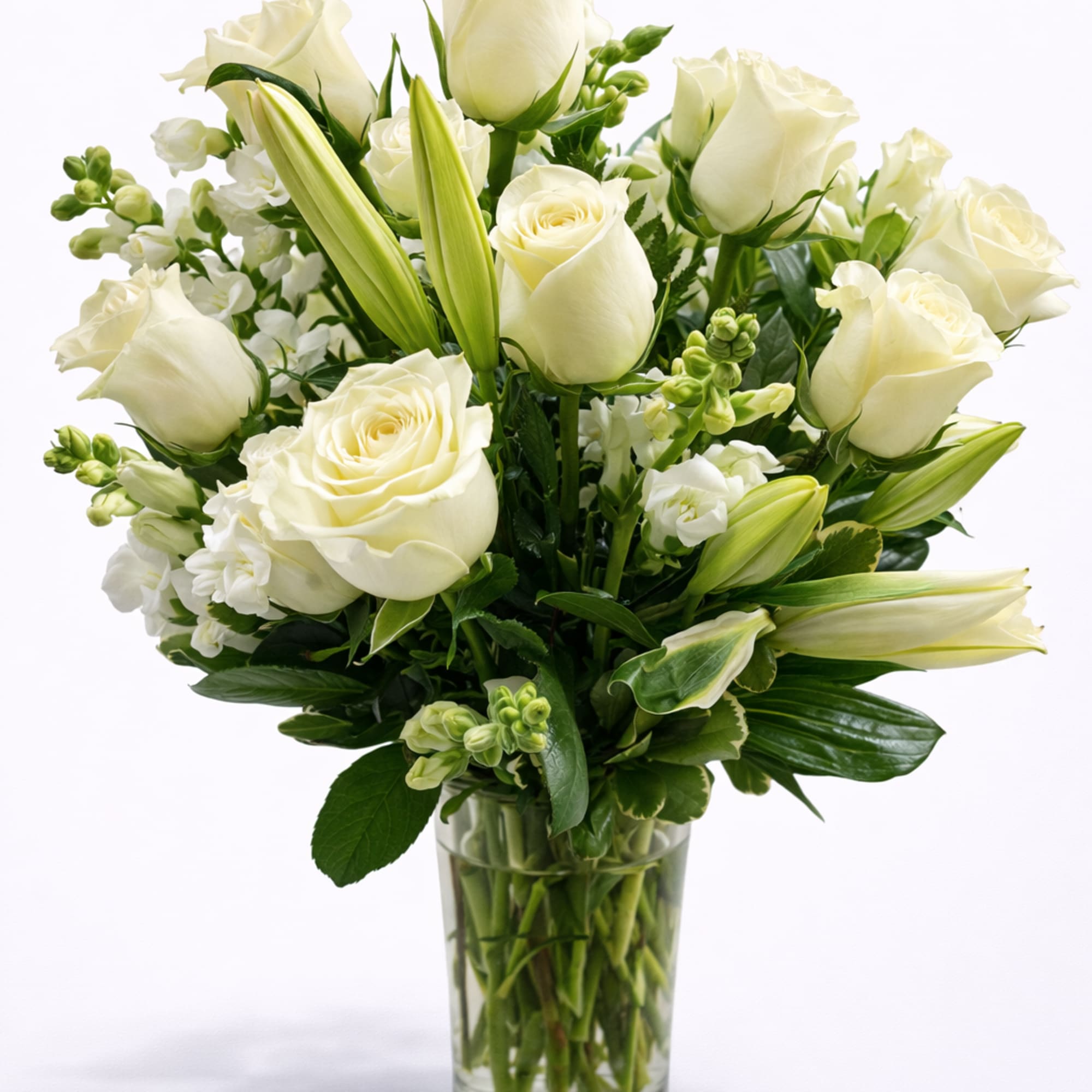 White roses and lilies arranged in a clear glass vase