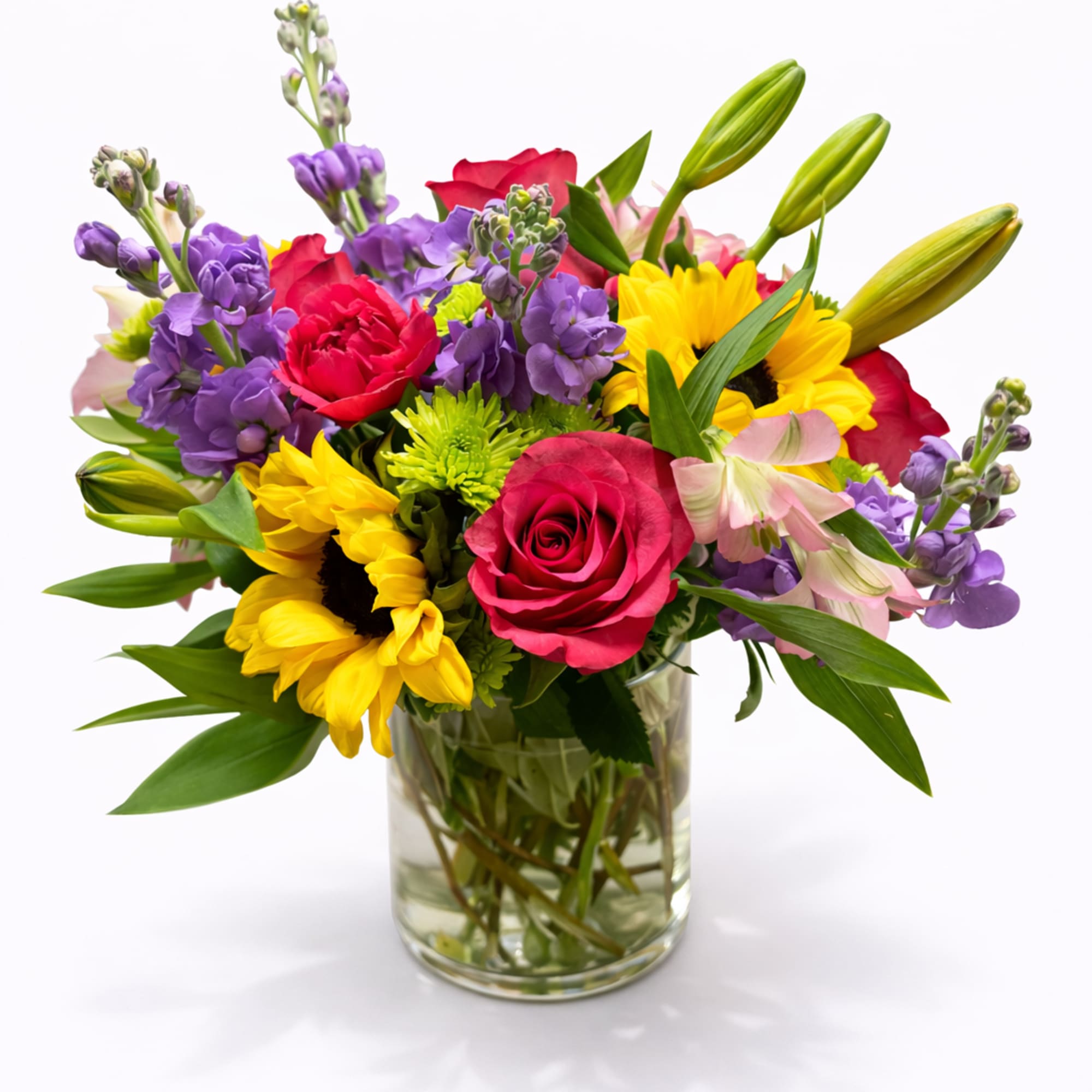 Mixed bouquet of roses, sunflowers, and lilies in a glass vase