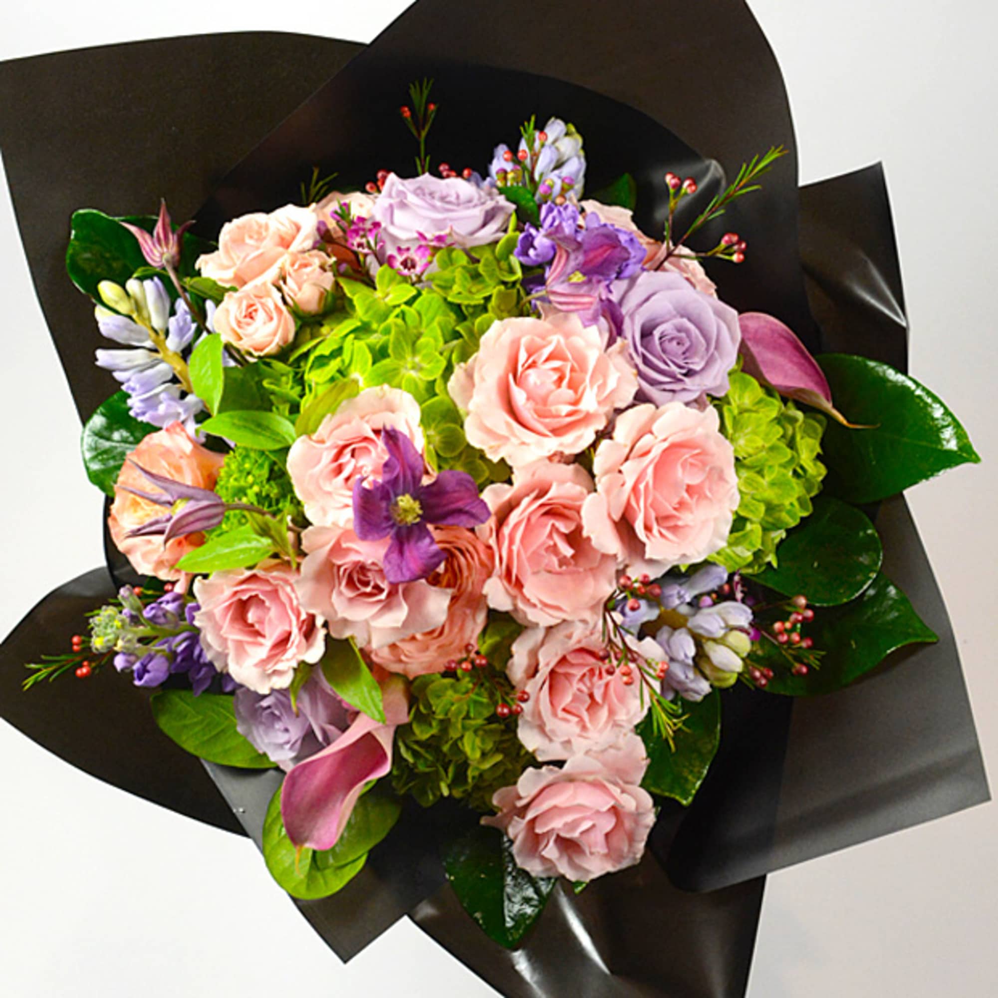 Bouquet of pink and lavender roses with green hydrangeas in black wrap