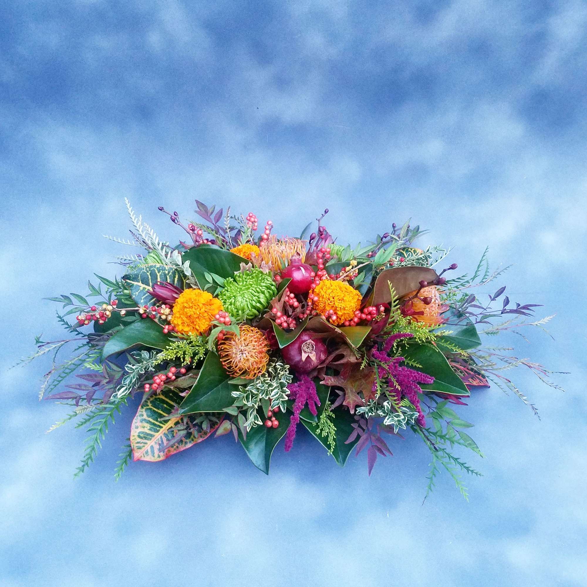 Low floral arrangement with orange, green, and purple blooms