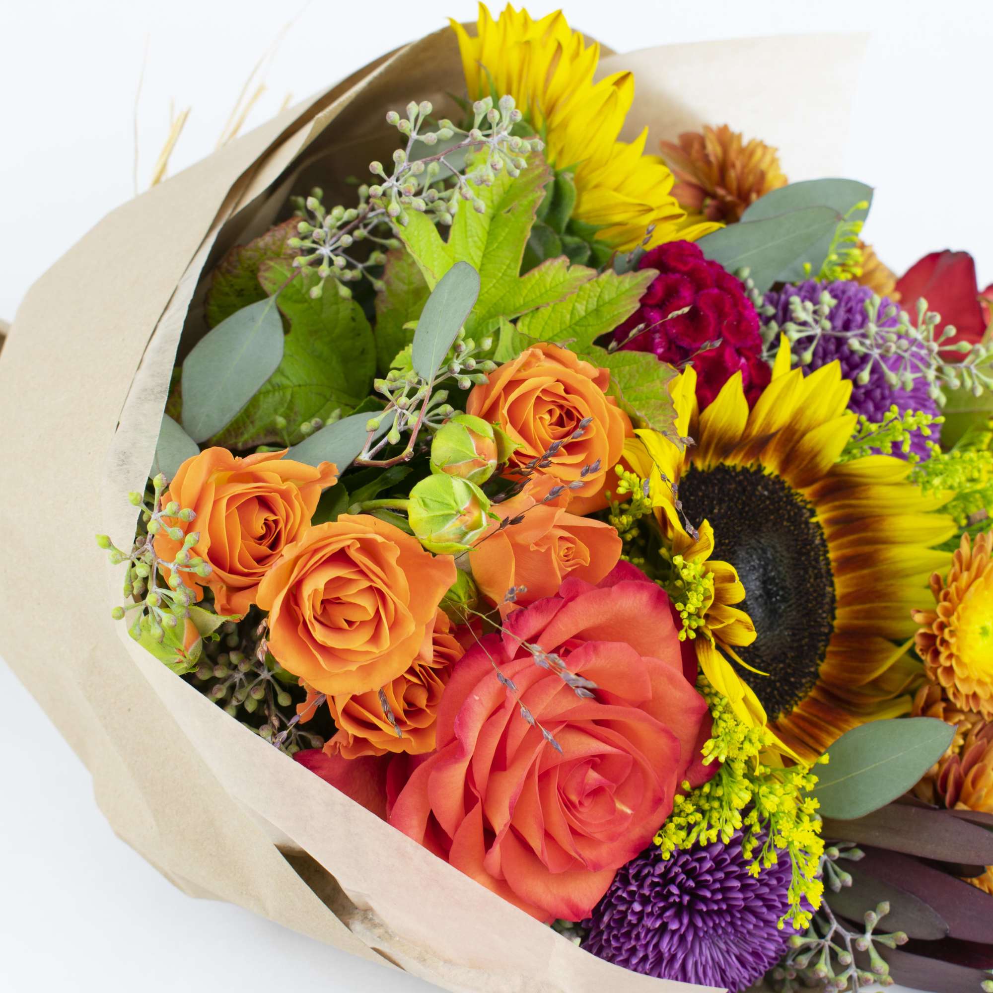 Bouquet of sunflowers, orange roses, and purple chrysanthemums in kraft paper