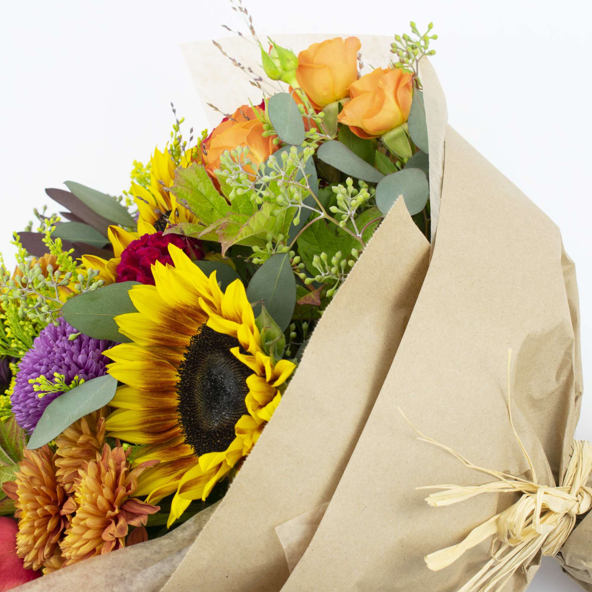 Bouquet of sunflowers, roses, and mixed blooms wrapped in kraft paper