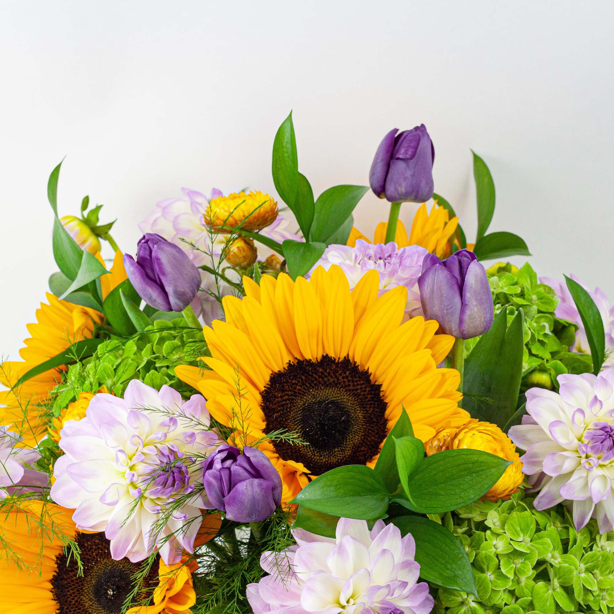Bouquet of sunflowers, purple tulips, and pale lavender dahlias