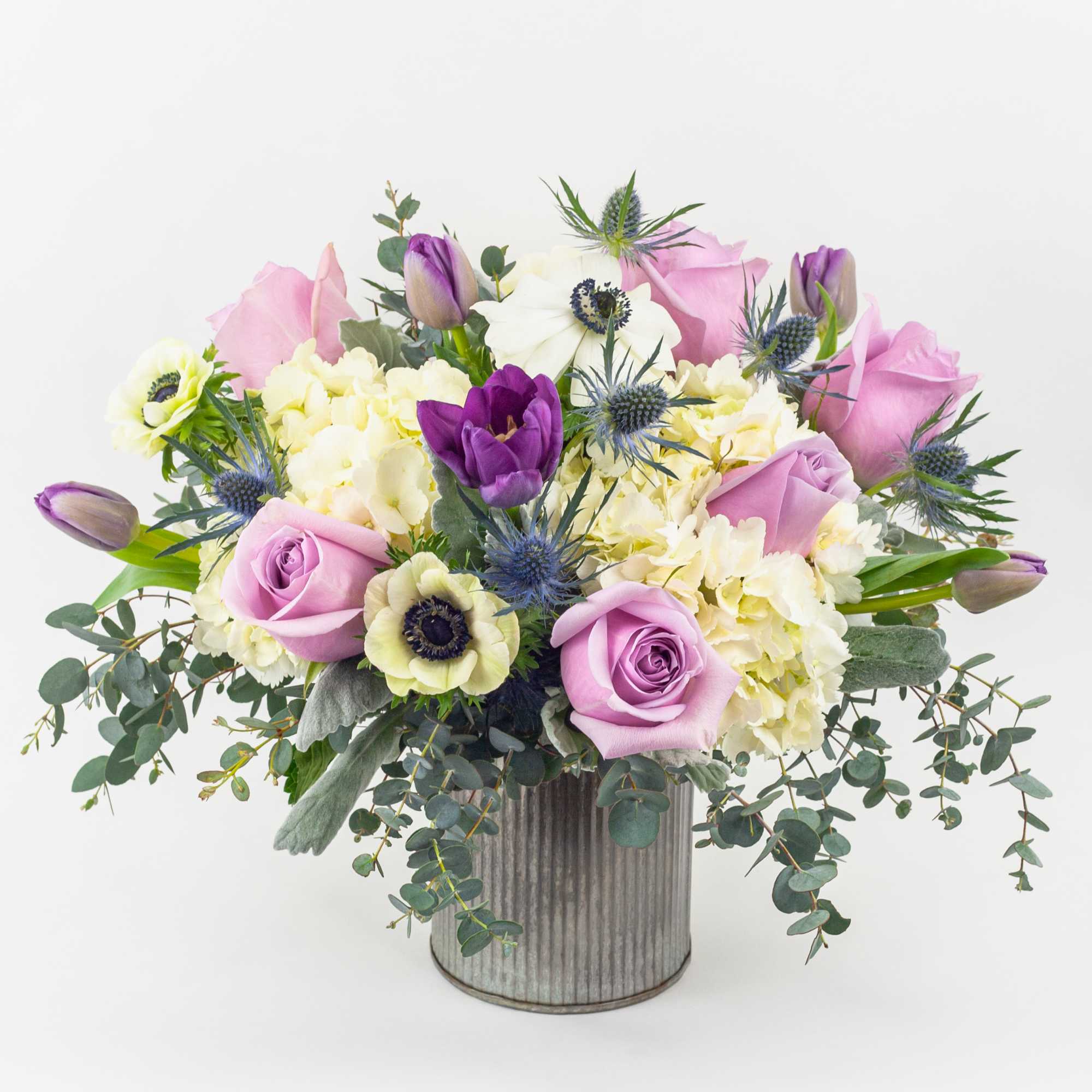 Pink and purple roses with white blooms in a ribbed metal vase