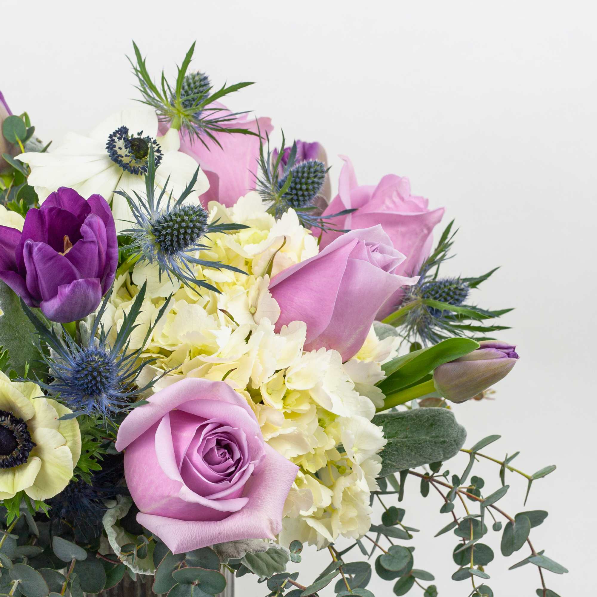 Bouquet of lavender roses, purple tulips, and pale yellow blooms