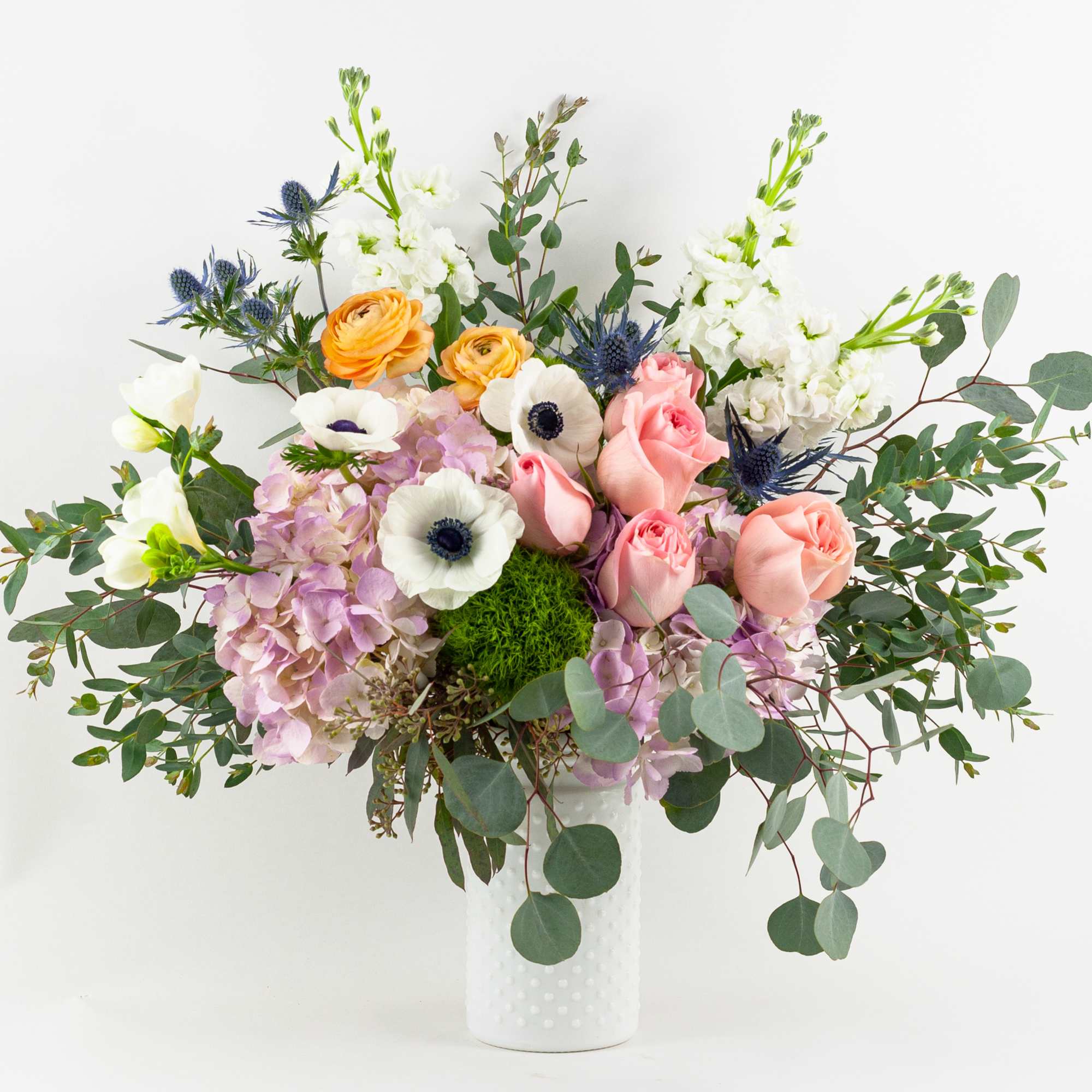 Mixed bouquet of pastel flowers in a white vase