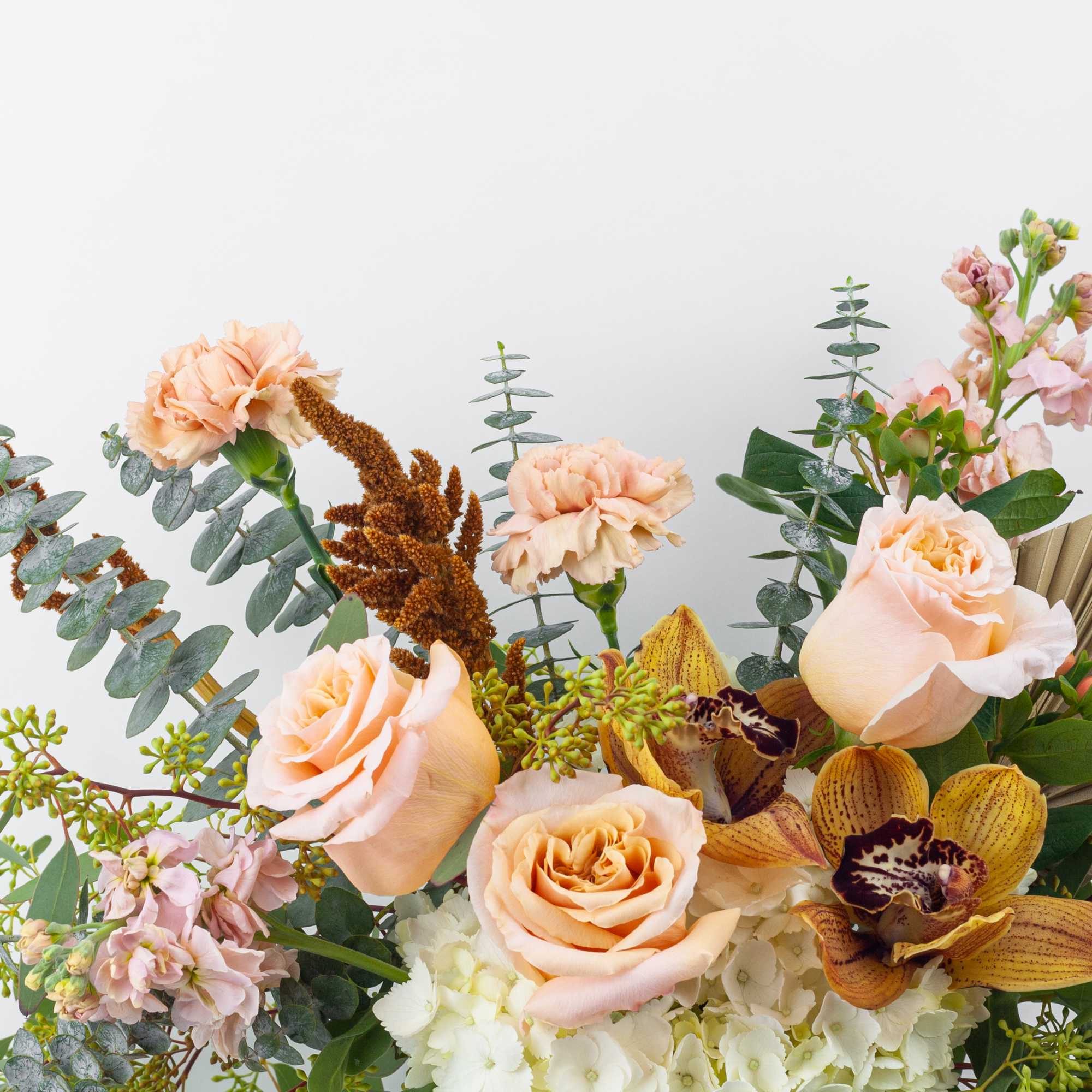 Peach roses and orchids arranged with pink flowers and greenery