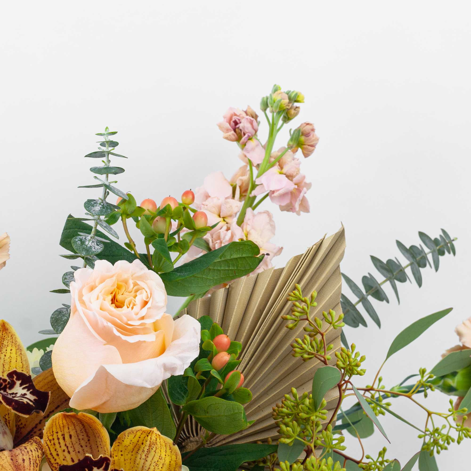 Peach roses and yellow orchids in a mixed bouquet with greenery
