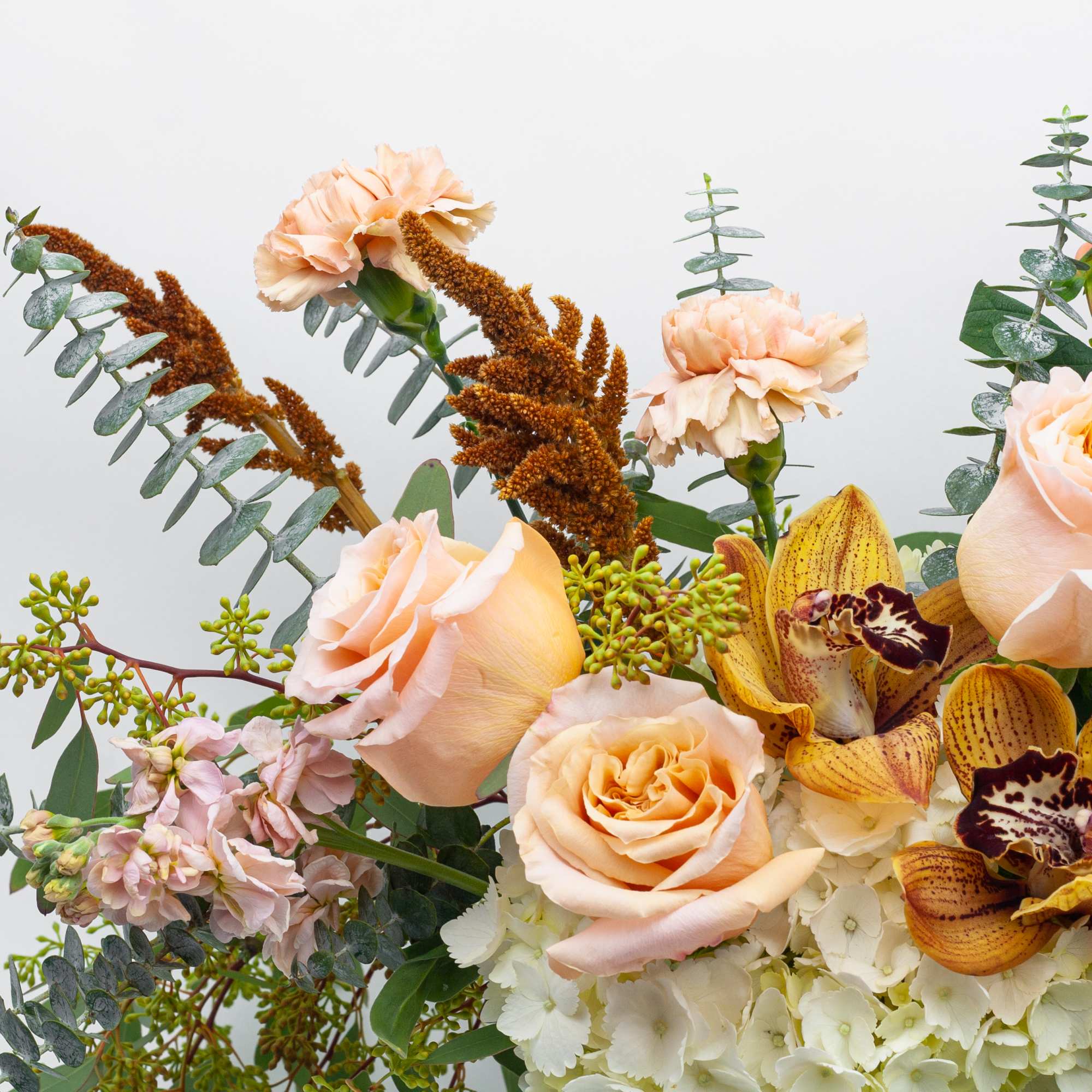 Peach roses and orchids in a mixed bouquet with eucalyptus