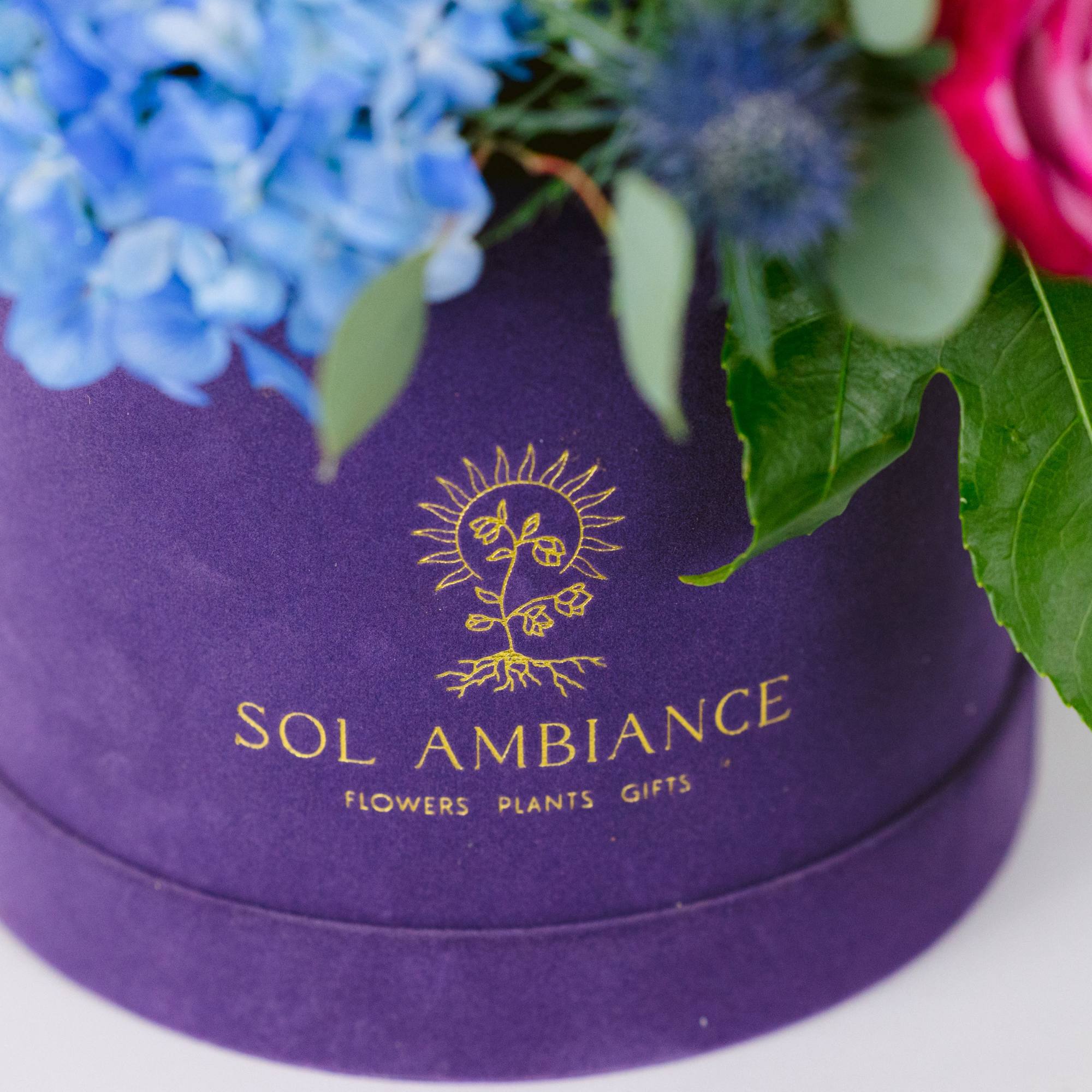 Pink and blue flowers in a purple hat box