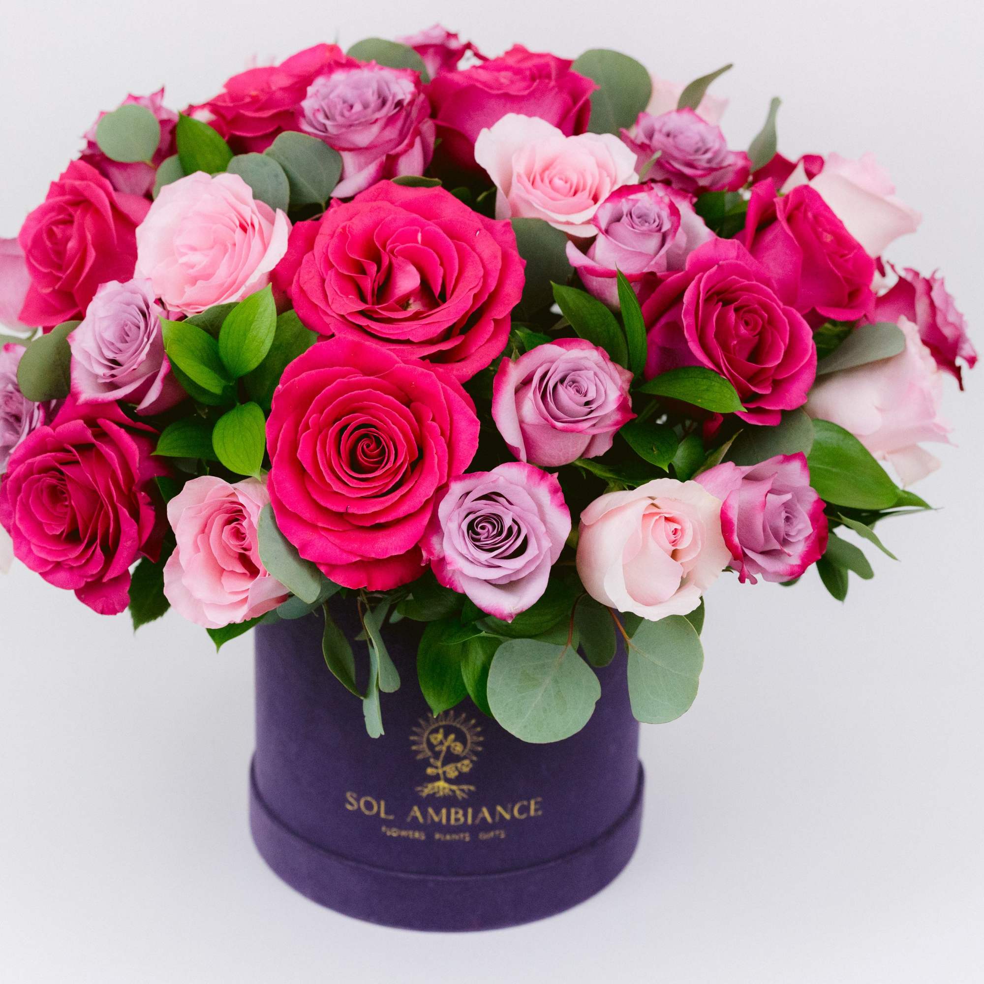Pink and lavender roses arranged in a purple hat box