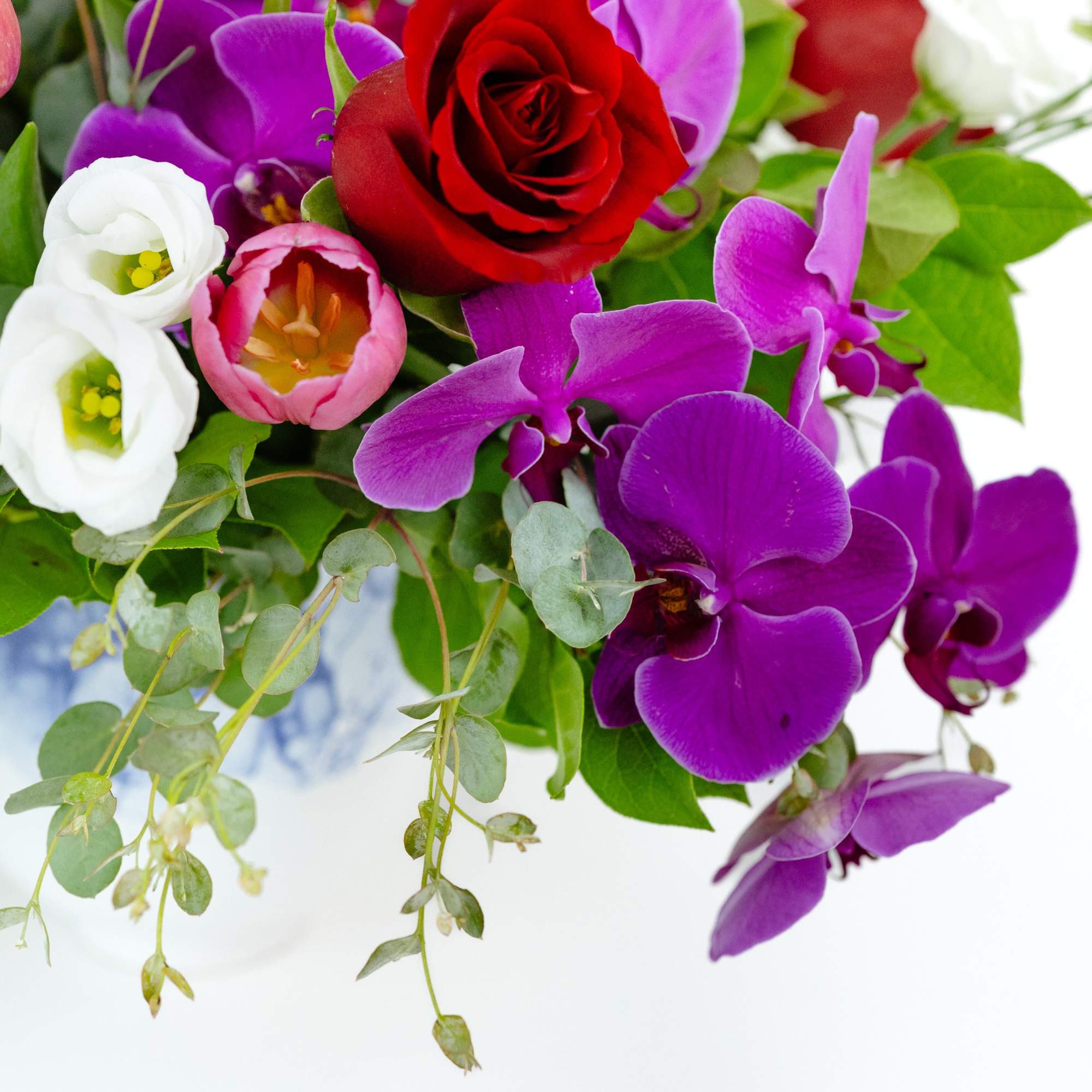 Bouquet of red roses, purple orchids, and white blooms with greenery