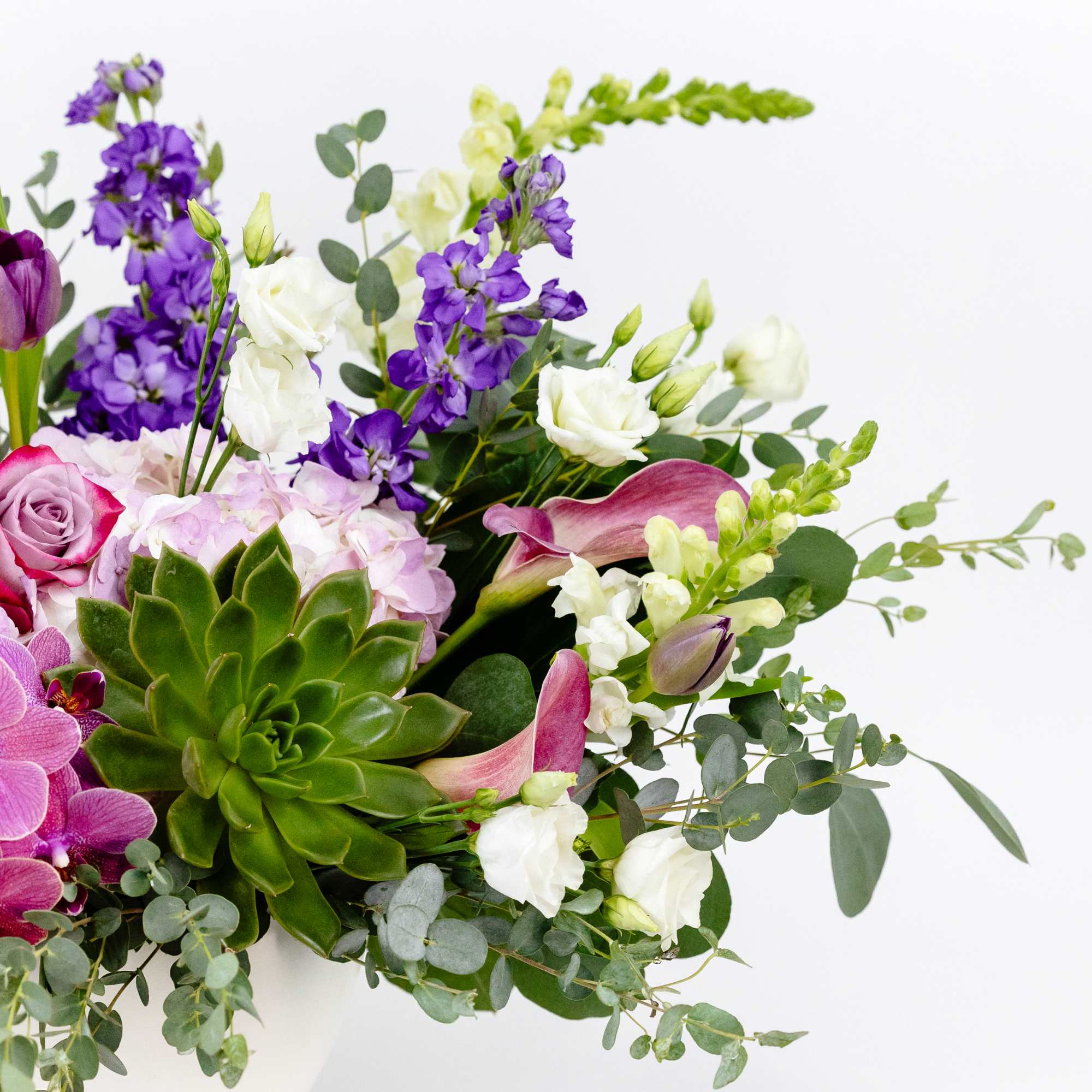 Mixed bouquet with purple orchids, roses, calla lilies, and a succulent