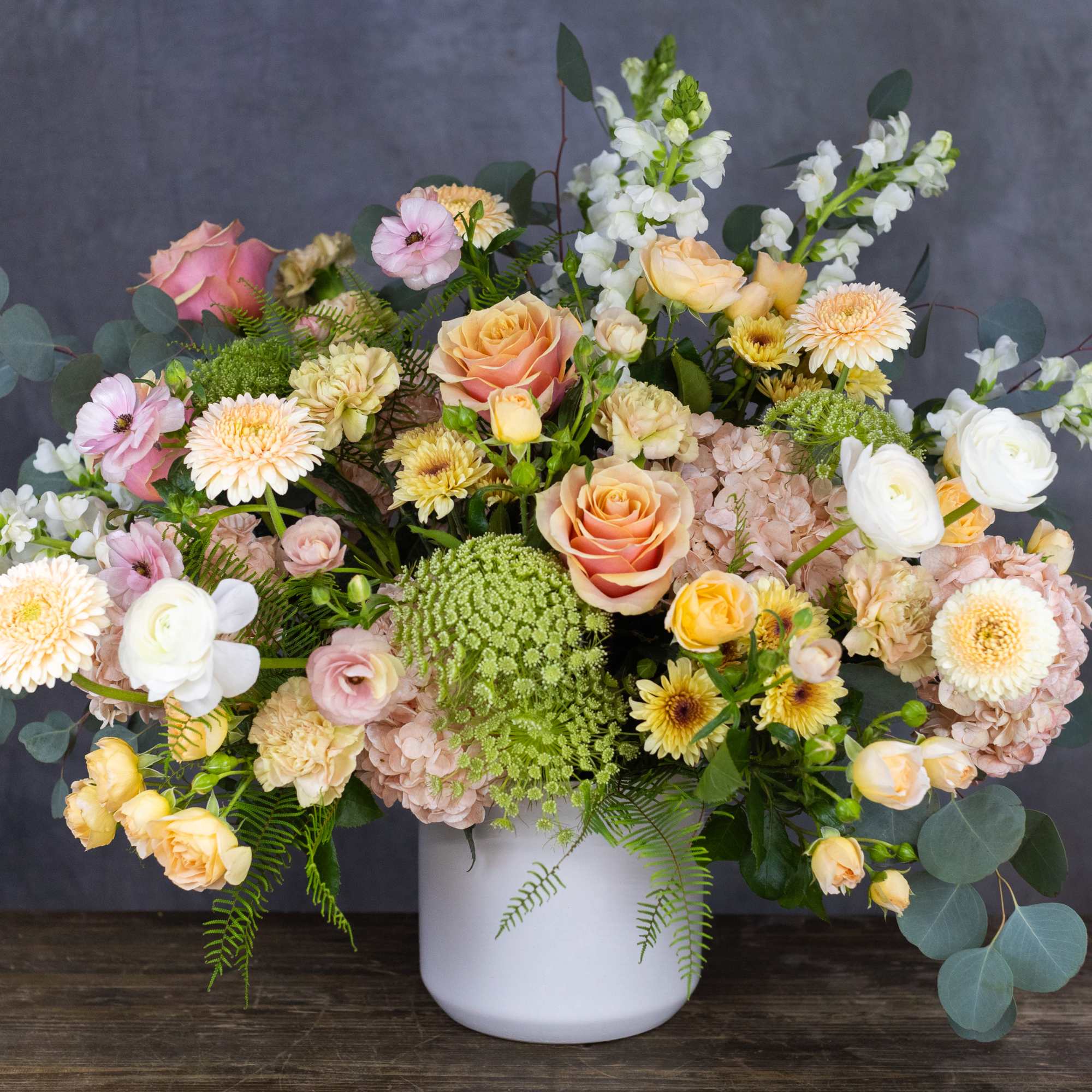 Mixed pastel flower arrangement in a white vase