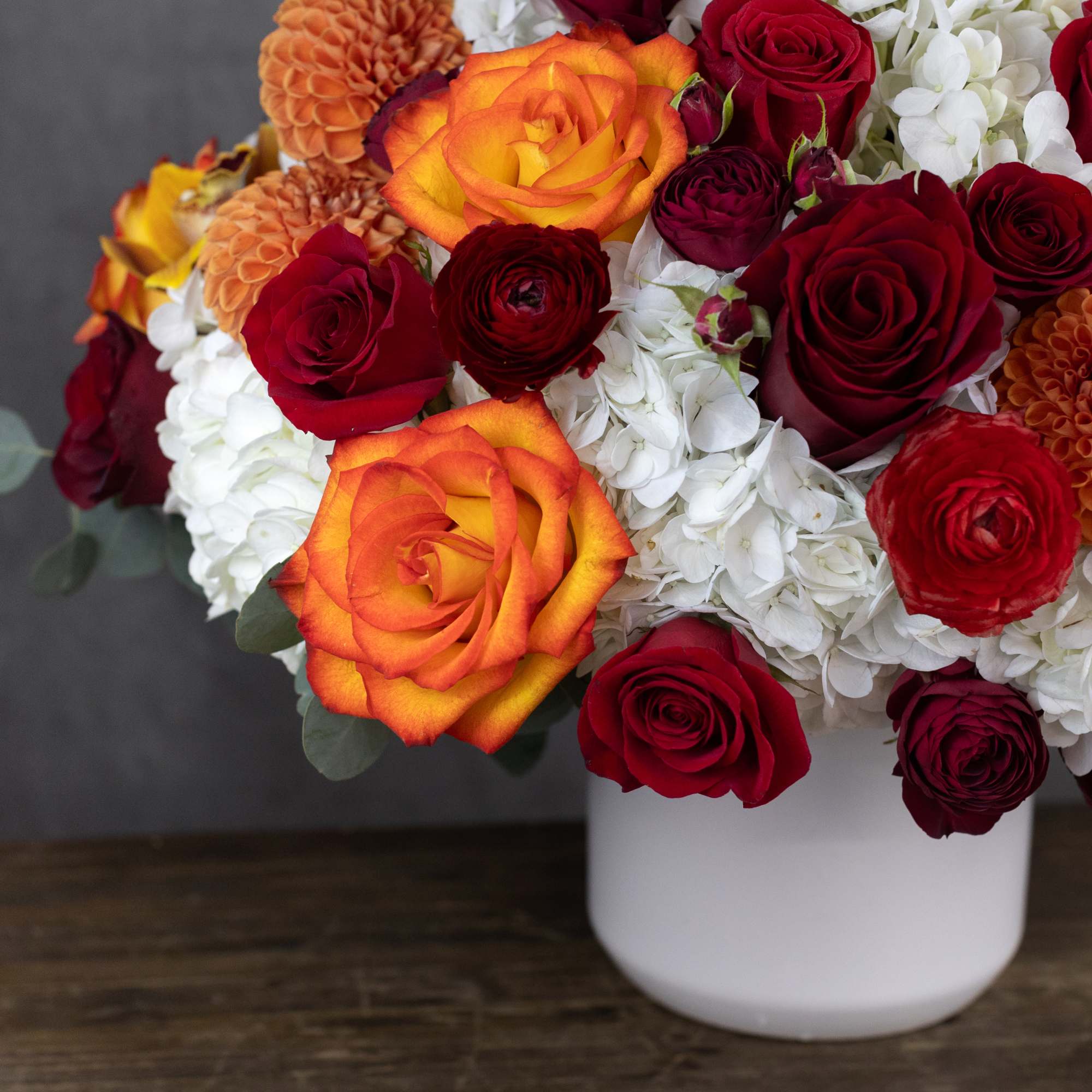 Bouquet of red and orange roses with white hydrangeas in a white vase, photo 3 of 5