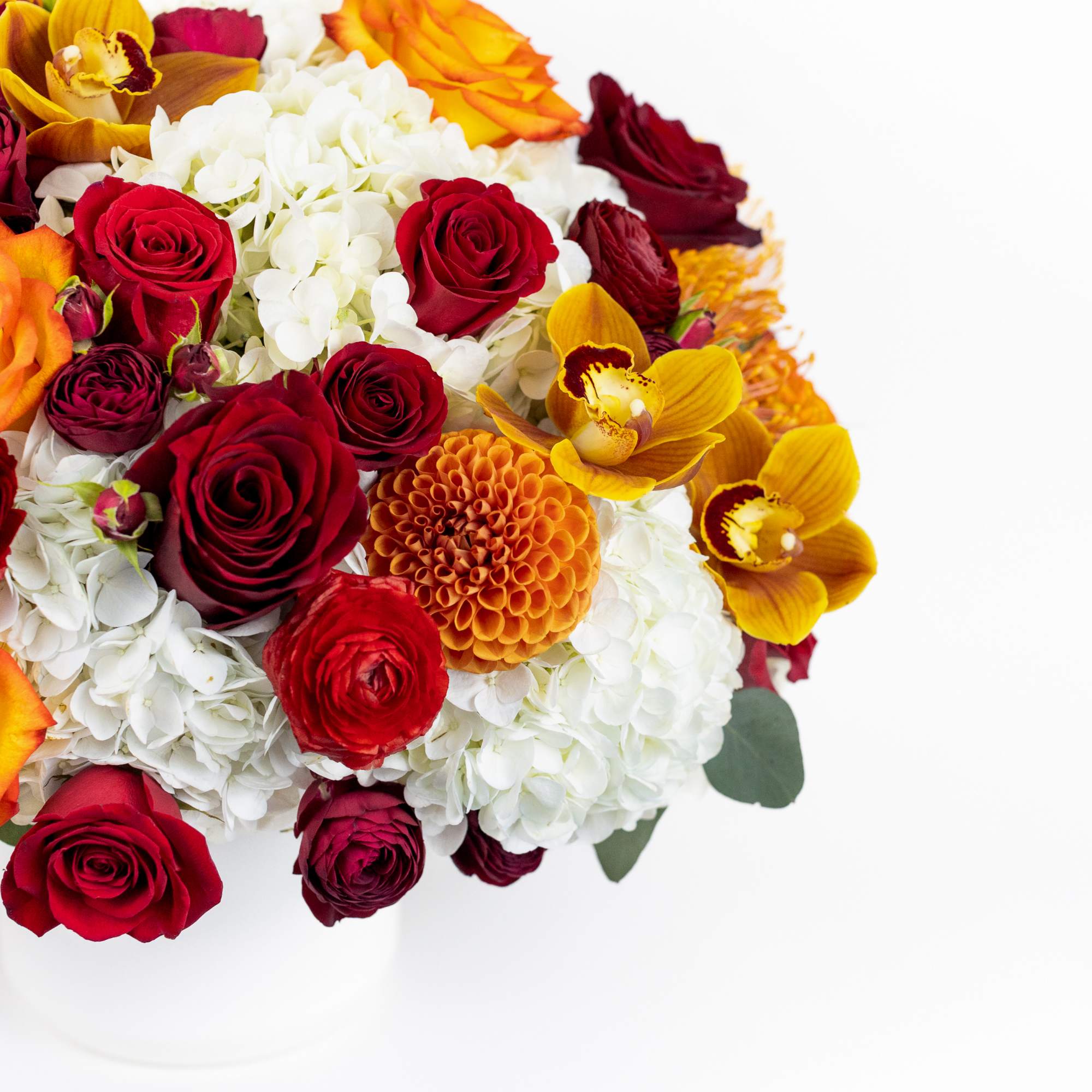 Bouquet of red and orange roses with white hydrangeas and yellow orchids in a white vase
