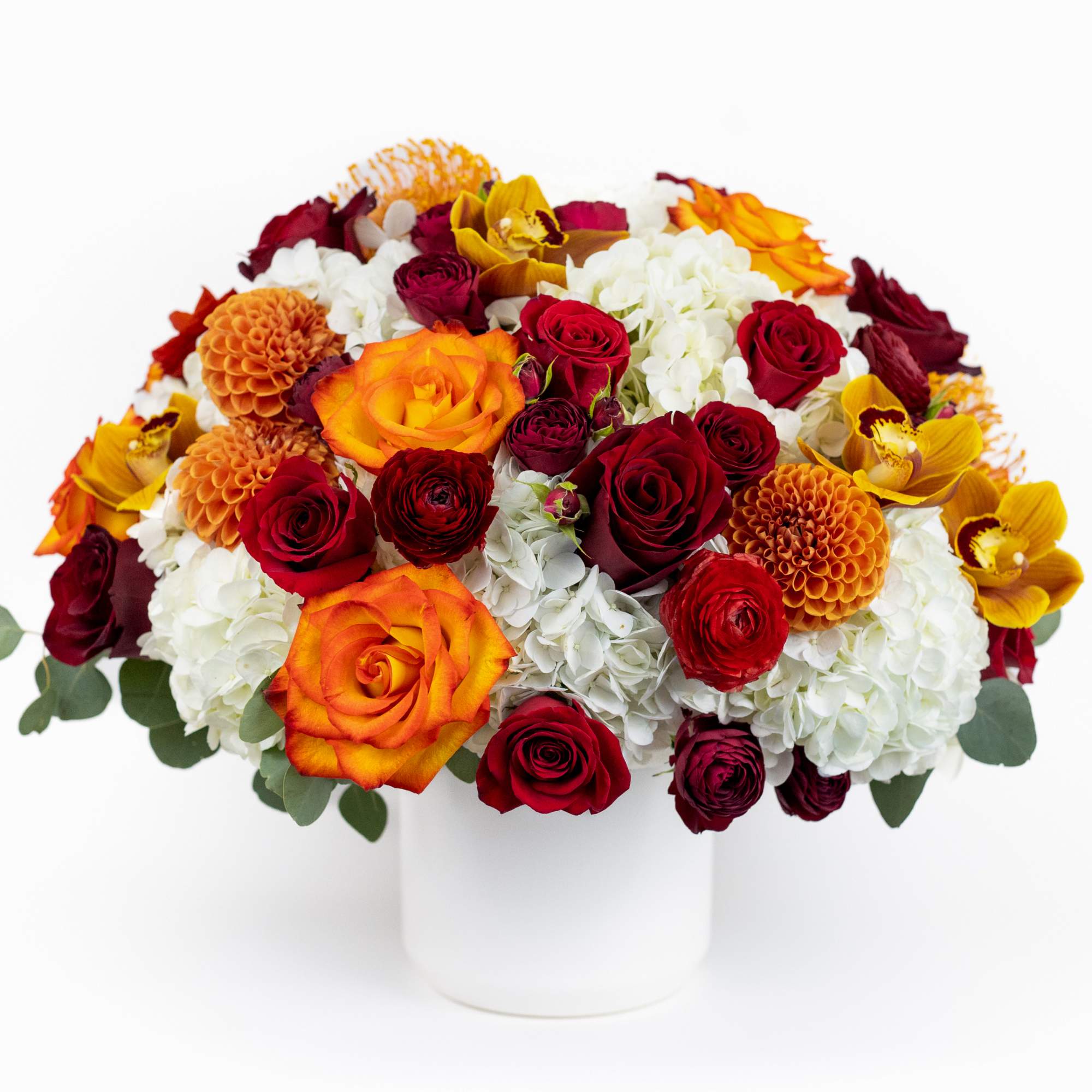 Mixed bouquet of red, orange, and white flowers in a white vase