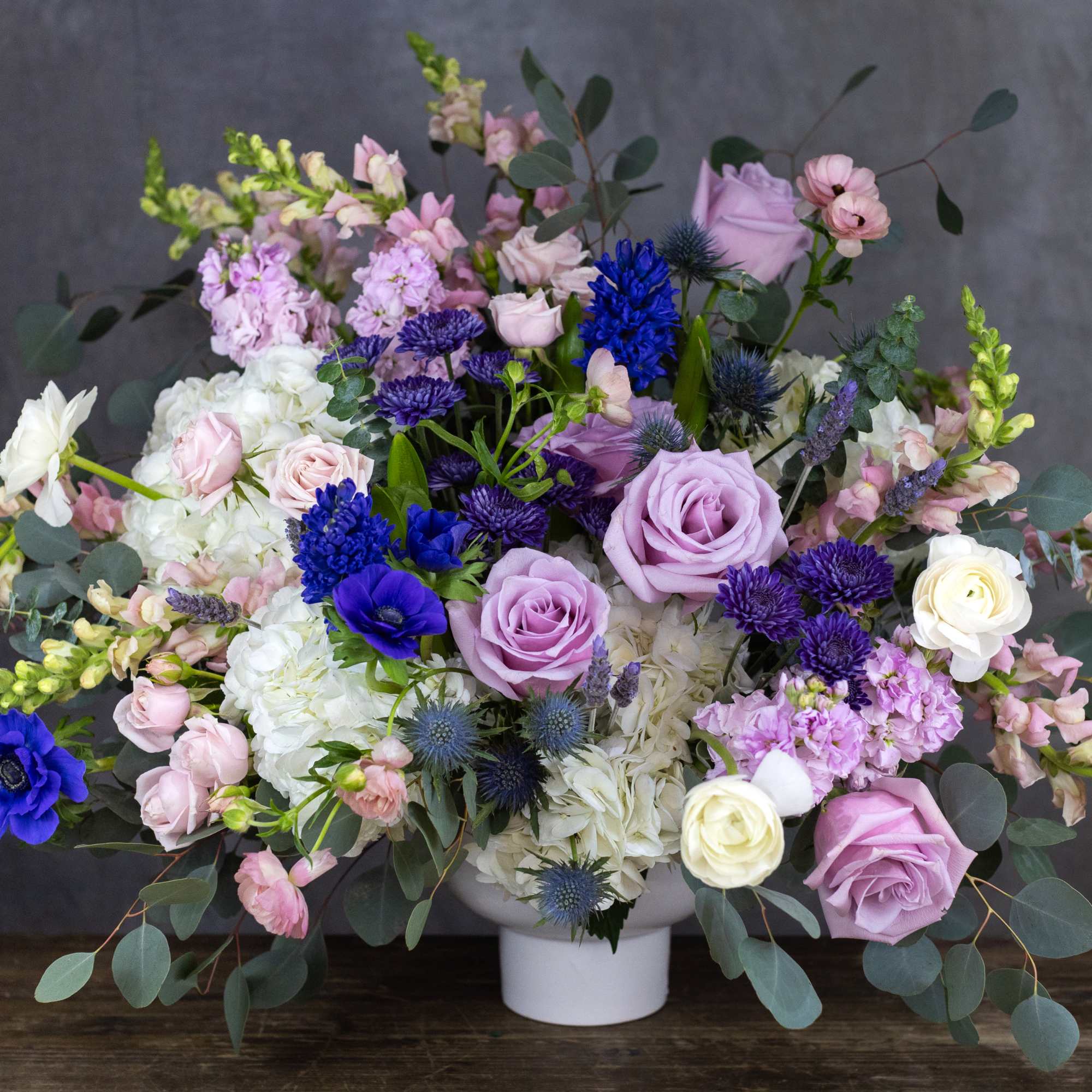 Lavender, white, and blue floral arrangement in a white vase