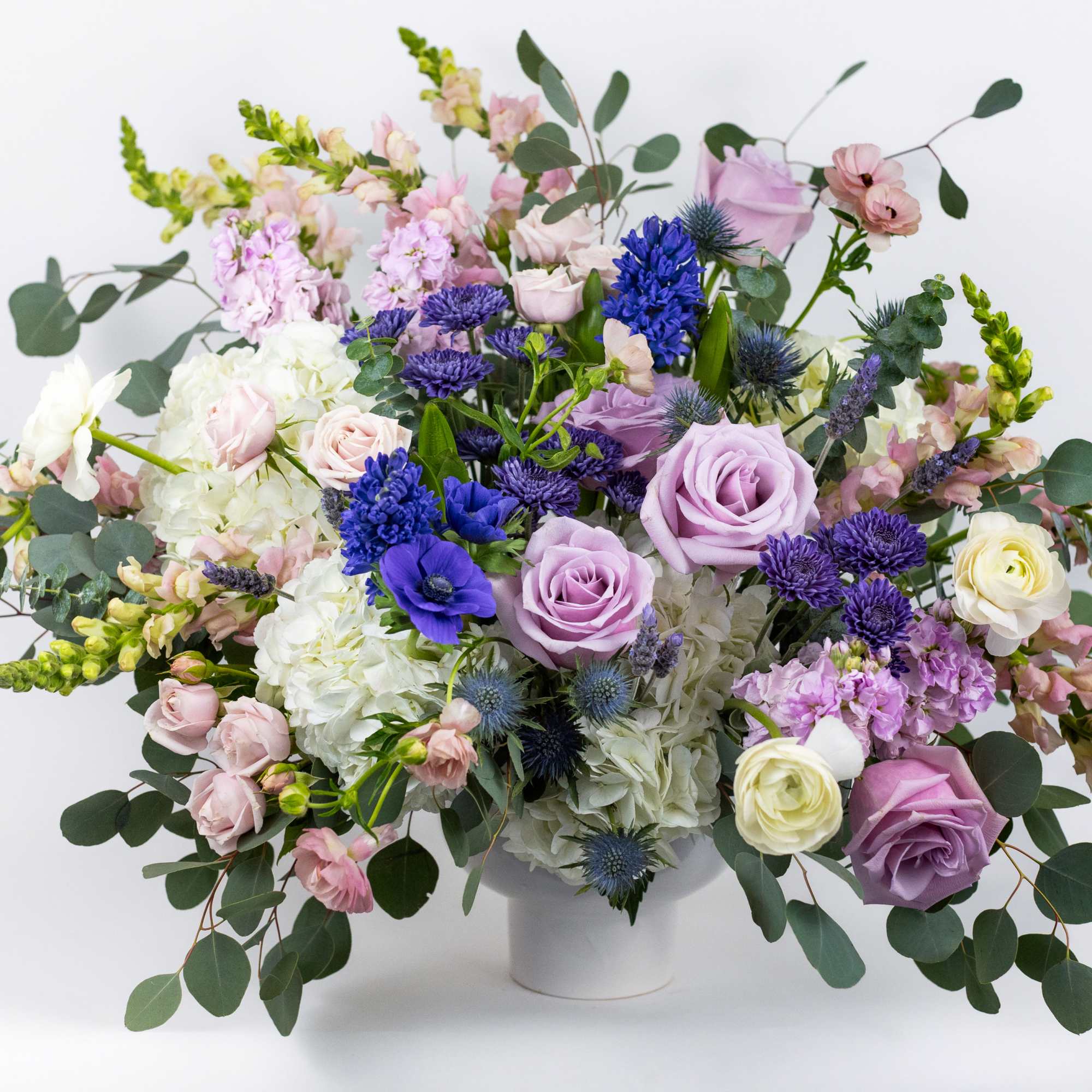 Lavender, pink, and white floral arrangement in a white vase