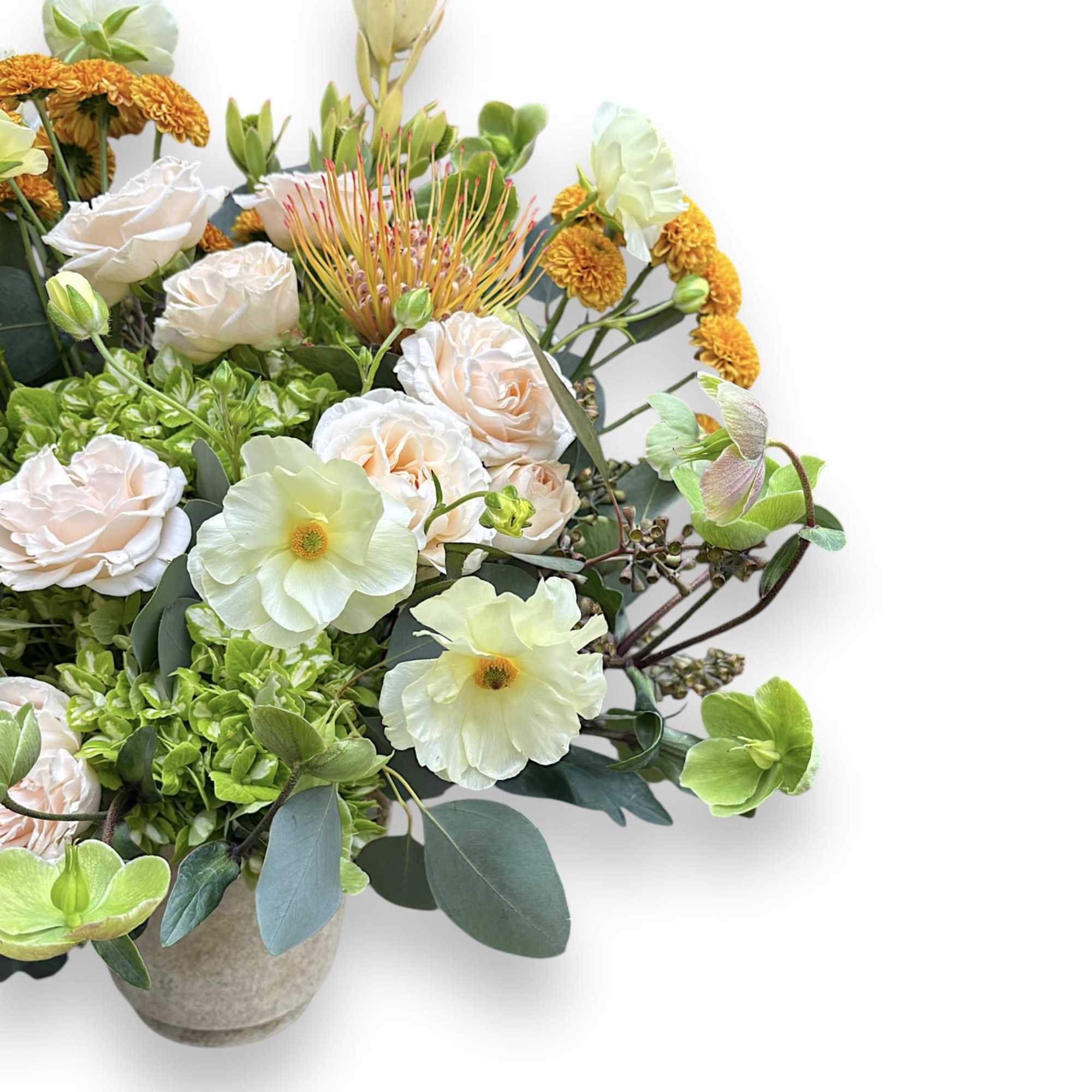 Mixed bouquet with pale roses, white blooms, and orange flowers in a vase