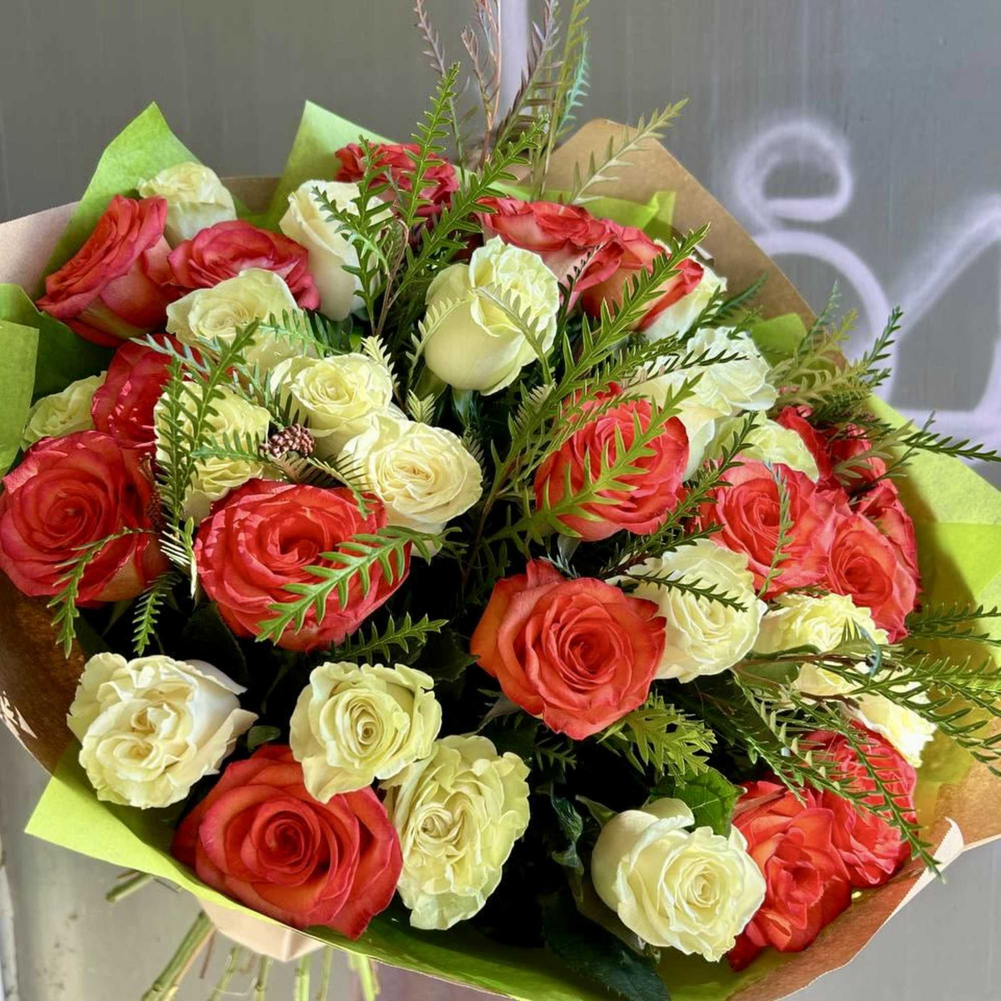 Bouquet of red and white roses wrapped in green and brown paper