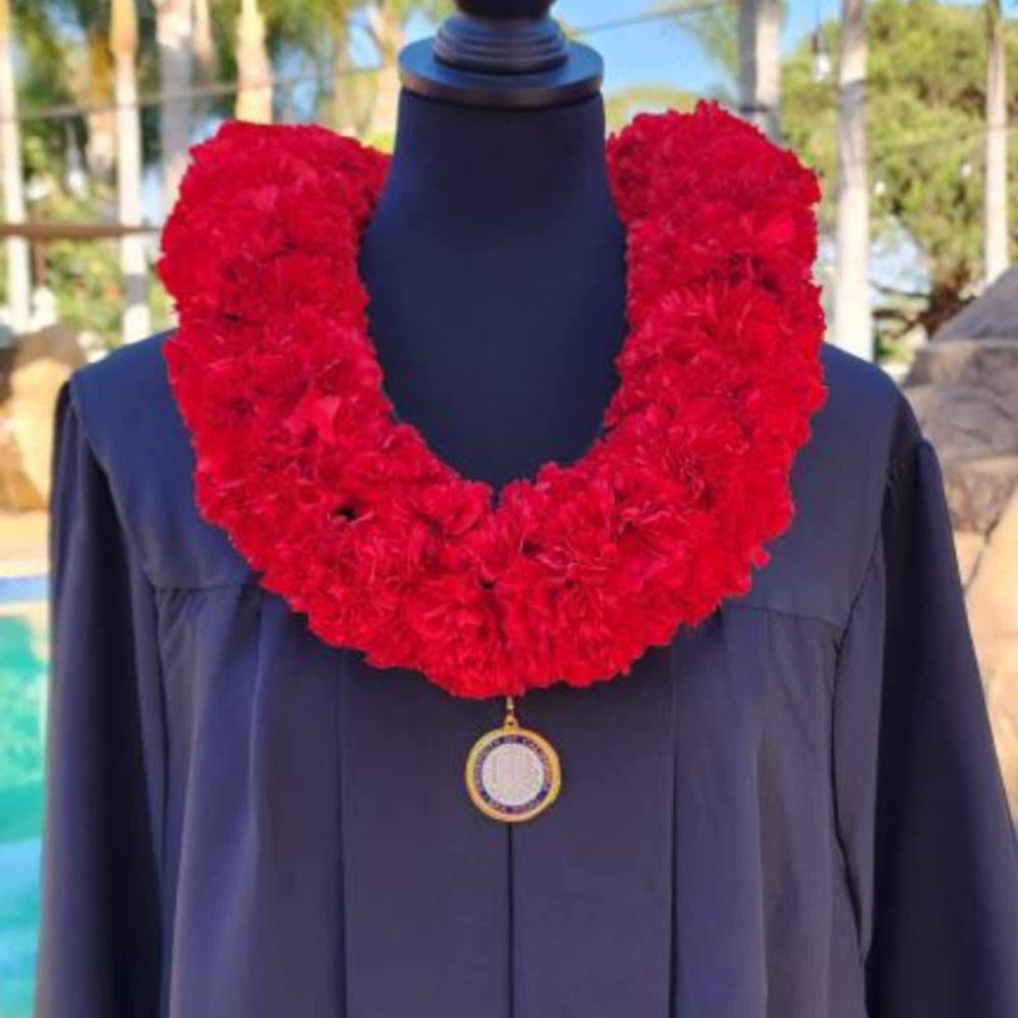 Red floral lei draped over a dark graduation gown