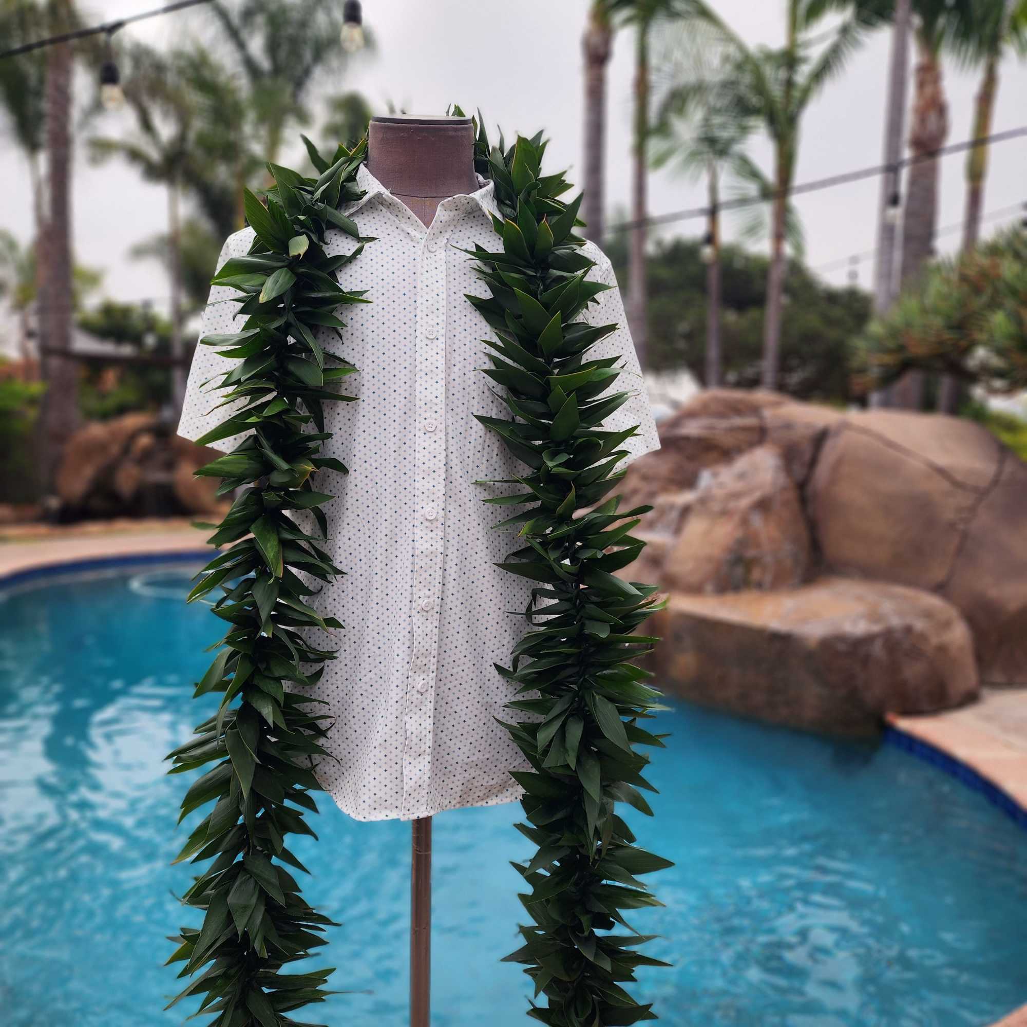 Leafy green lei draped over a white shirt on a mannequin