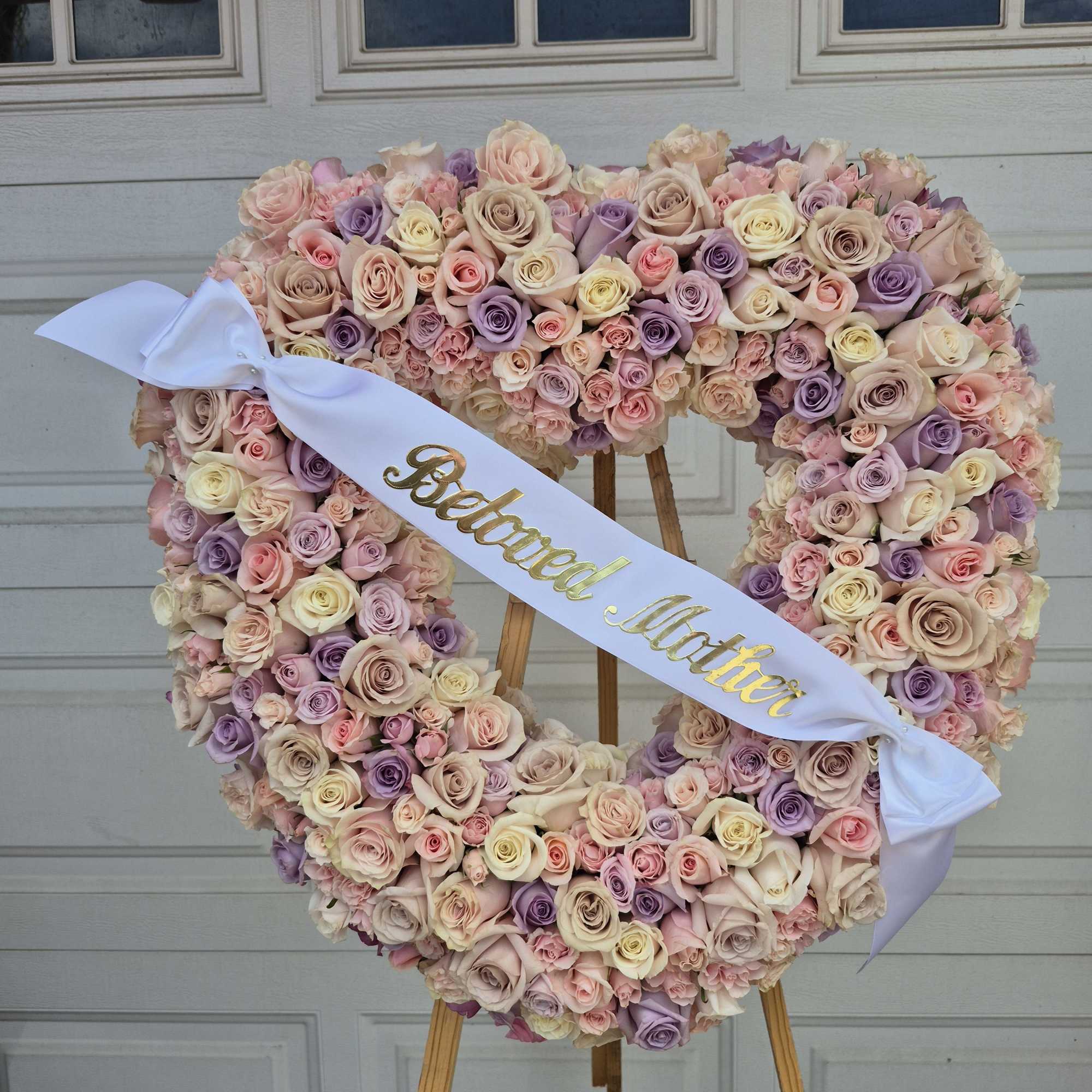 Heart-shaped rose wreath on an easel with a "Beloved Mother" ribbon