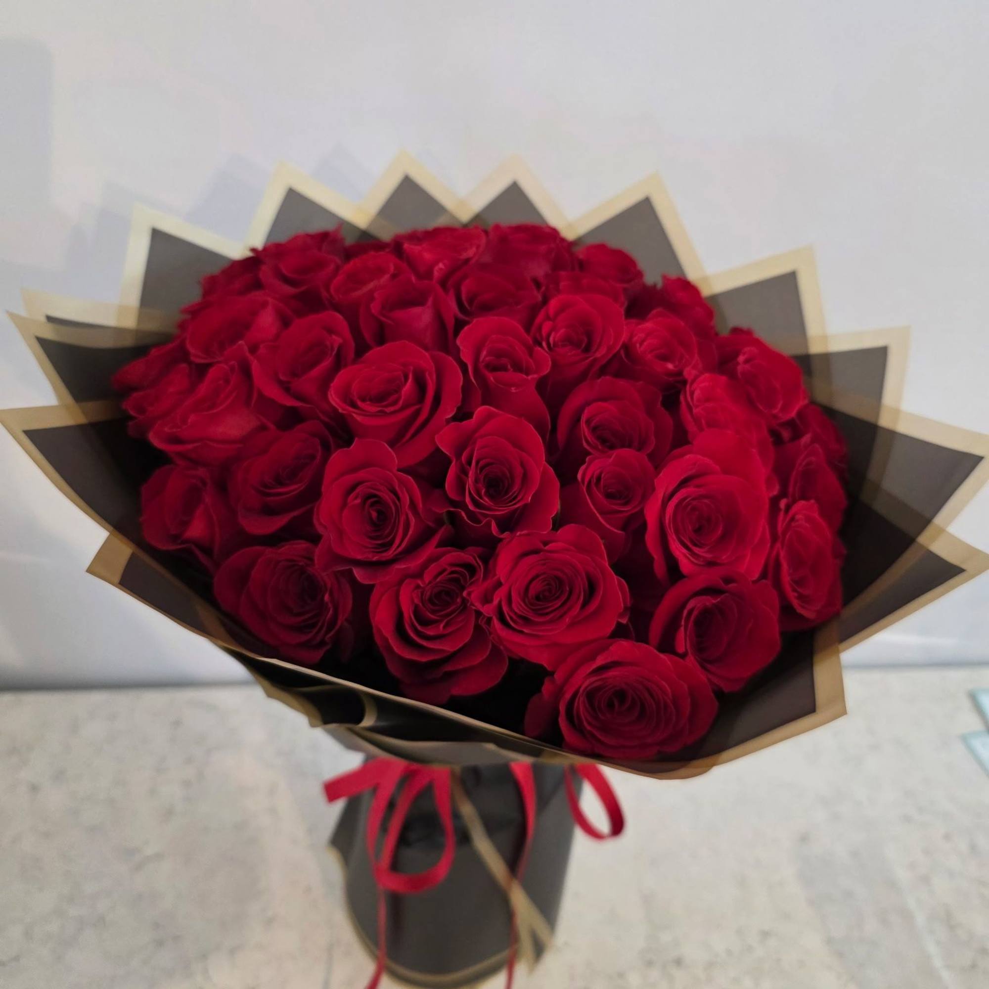 Bouquet of red roses wrapped in black and gold paper with a red ribbon