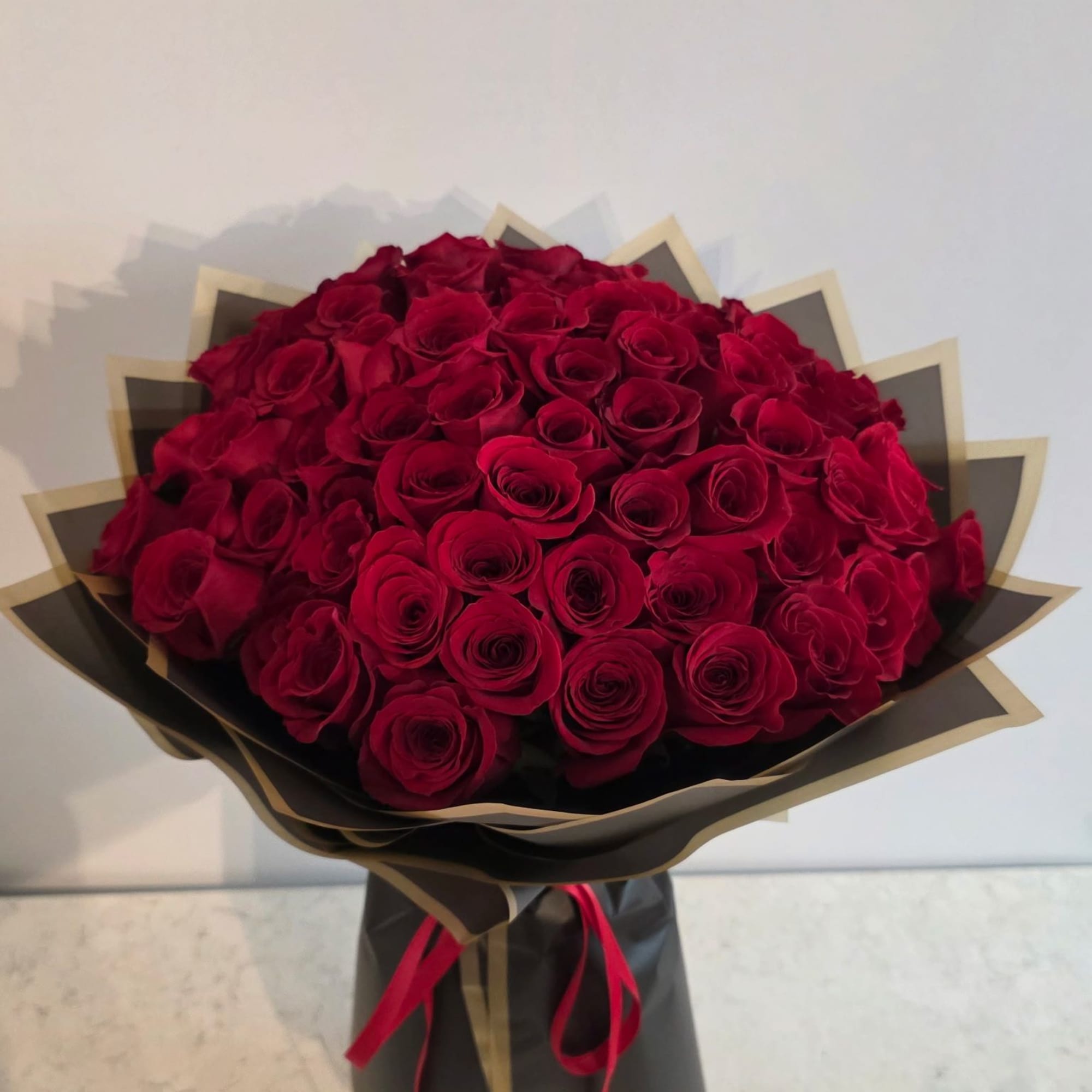 Large bouquet of red roses wrapped in black and gold paper