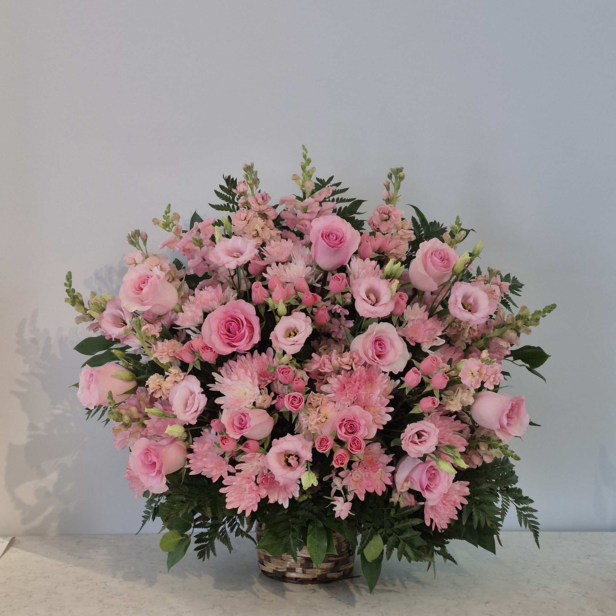 Large pink flower arrangement in a woven basket