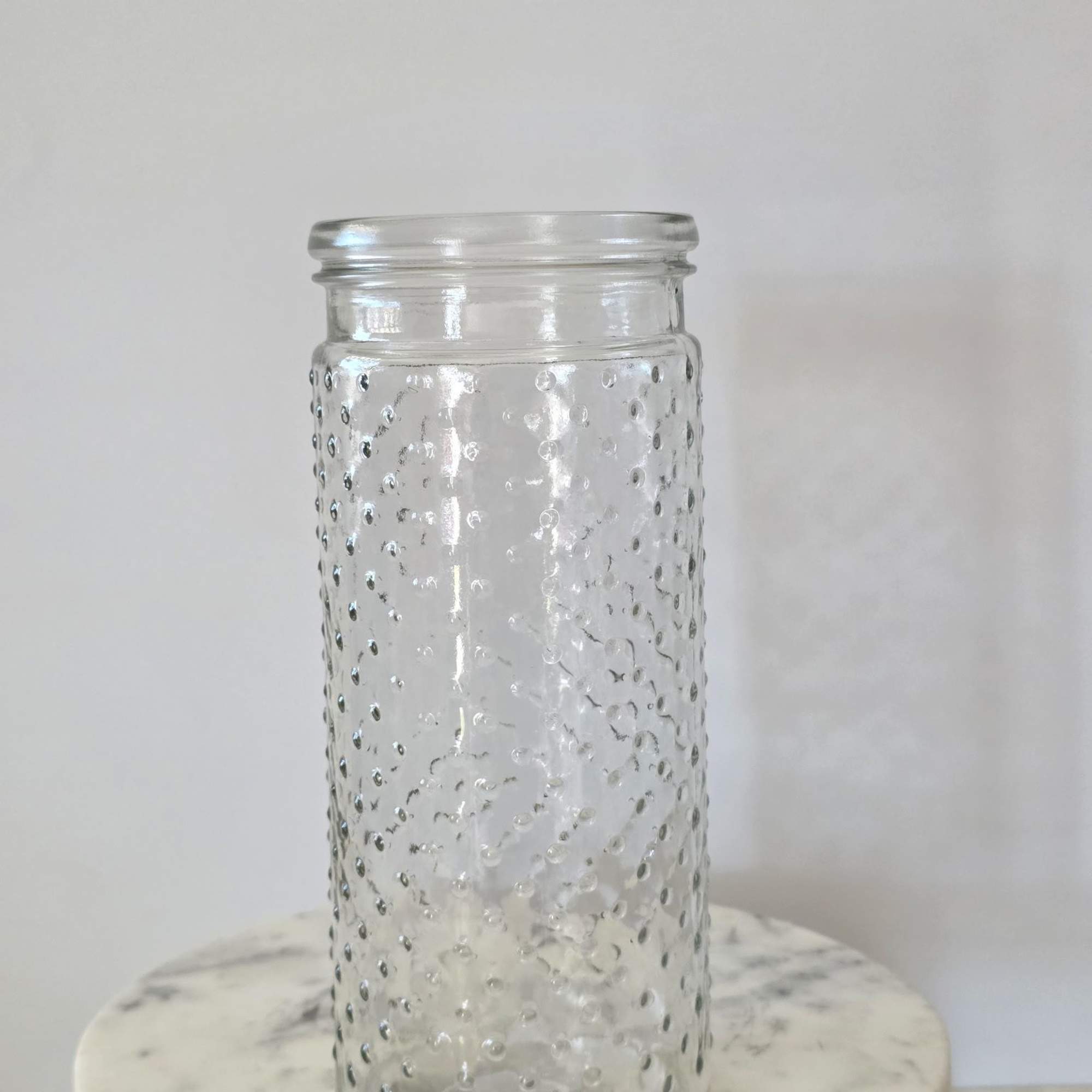 Clear textured glass vase on a round marble stand