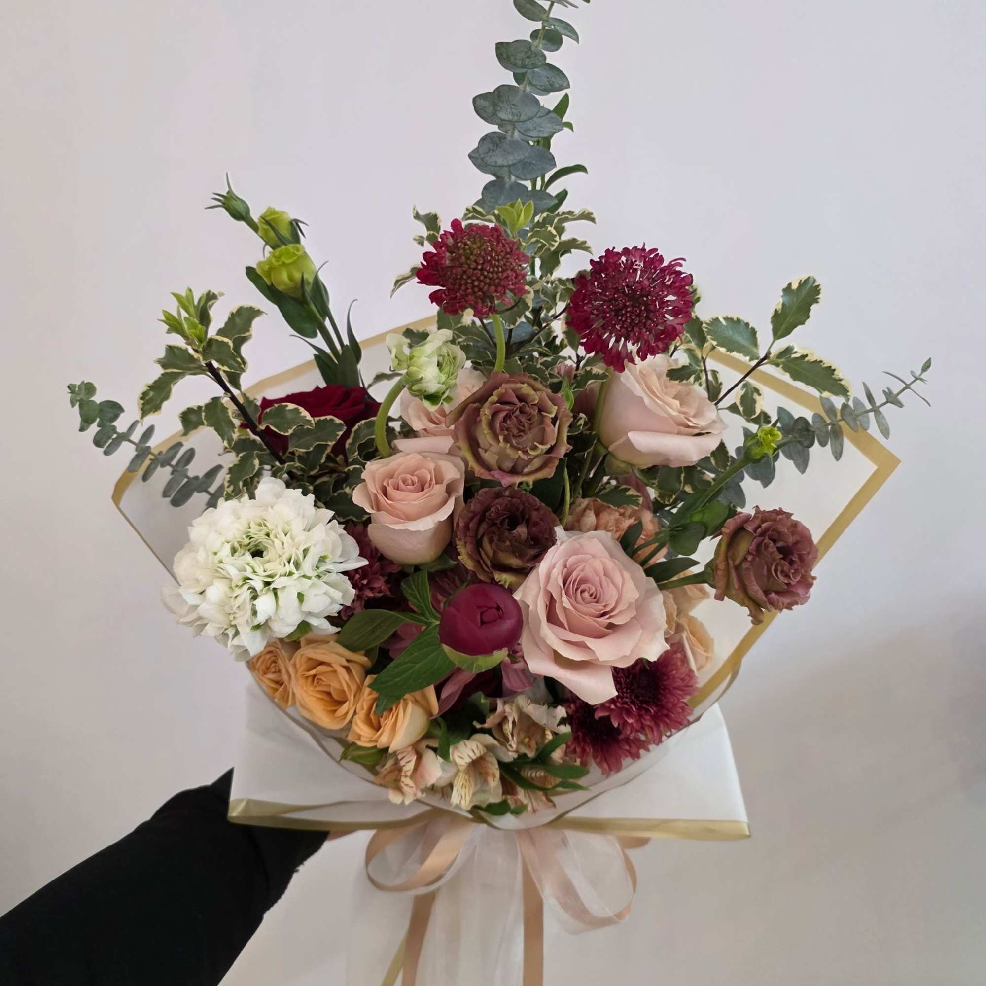 Hand-tied bouquet of roses and mixed blooms with eucalyptus and ribbon wrap