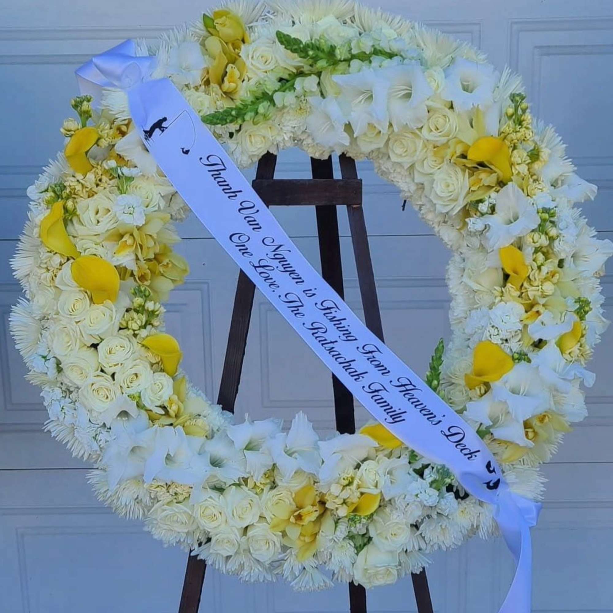 A luminous circle of white roses and chrysanthemums forms the calm, respectful