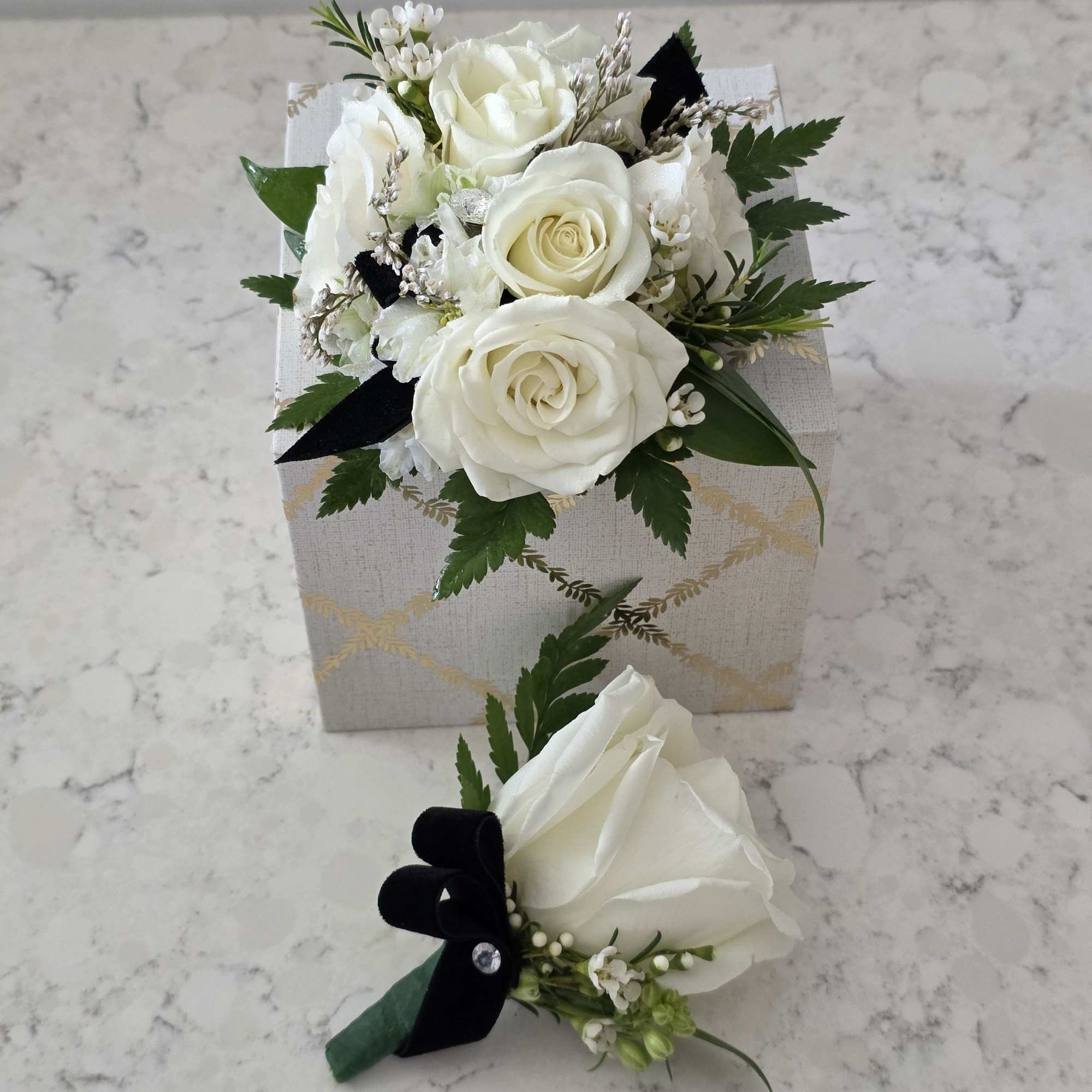 A cluster of pure white roses tied with dark ribbon makes an