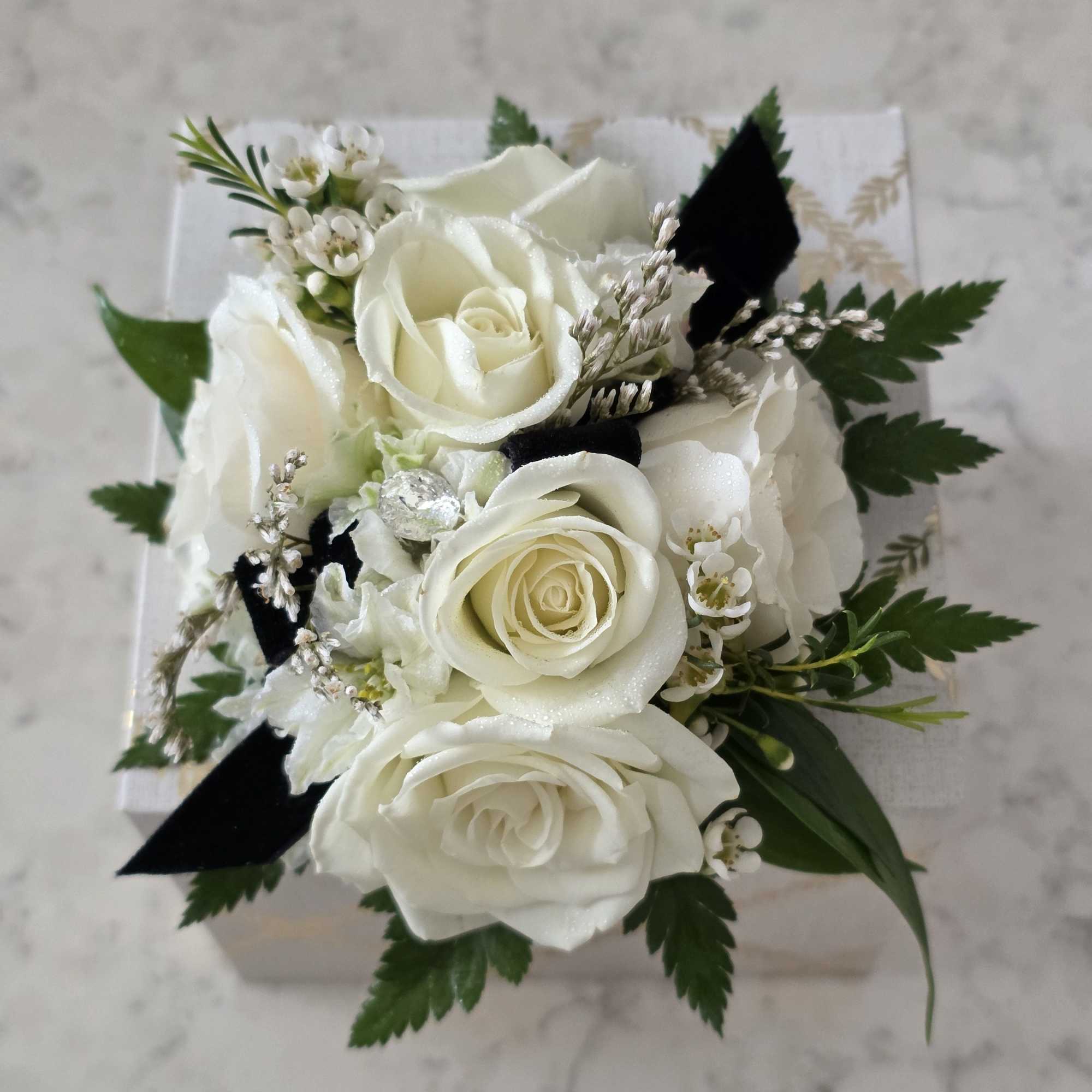A cluster of pure white roses tied with dark ribbon makes an
