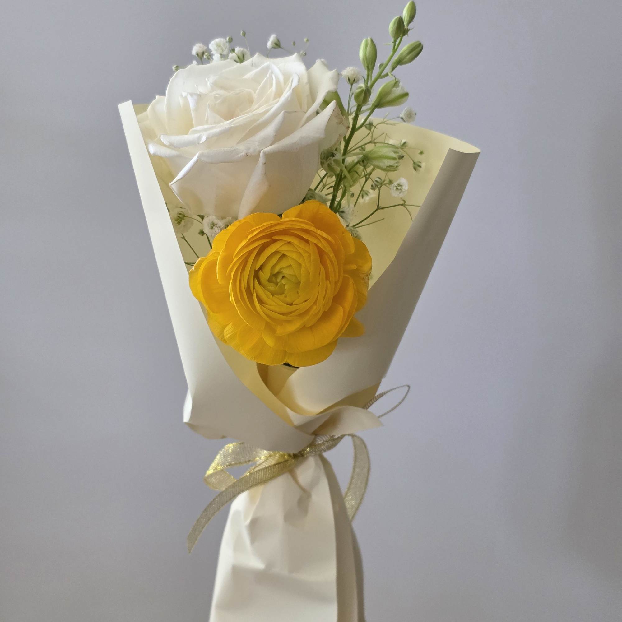 A bright yellow ranunculus paired with a creamy white rose makes this