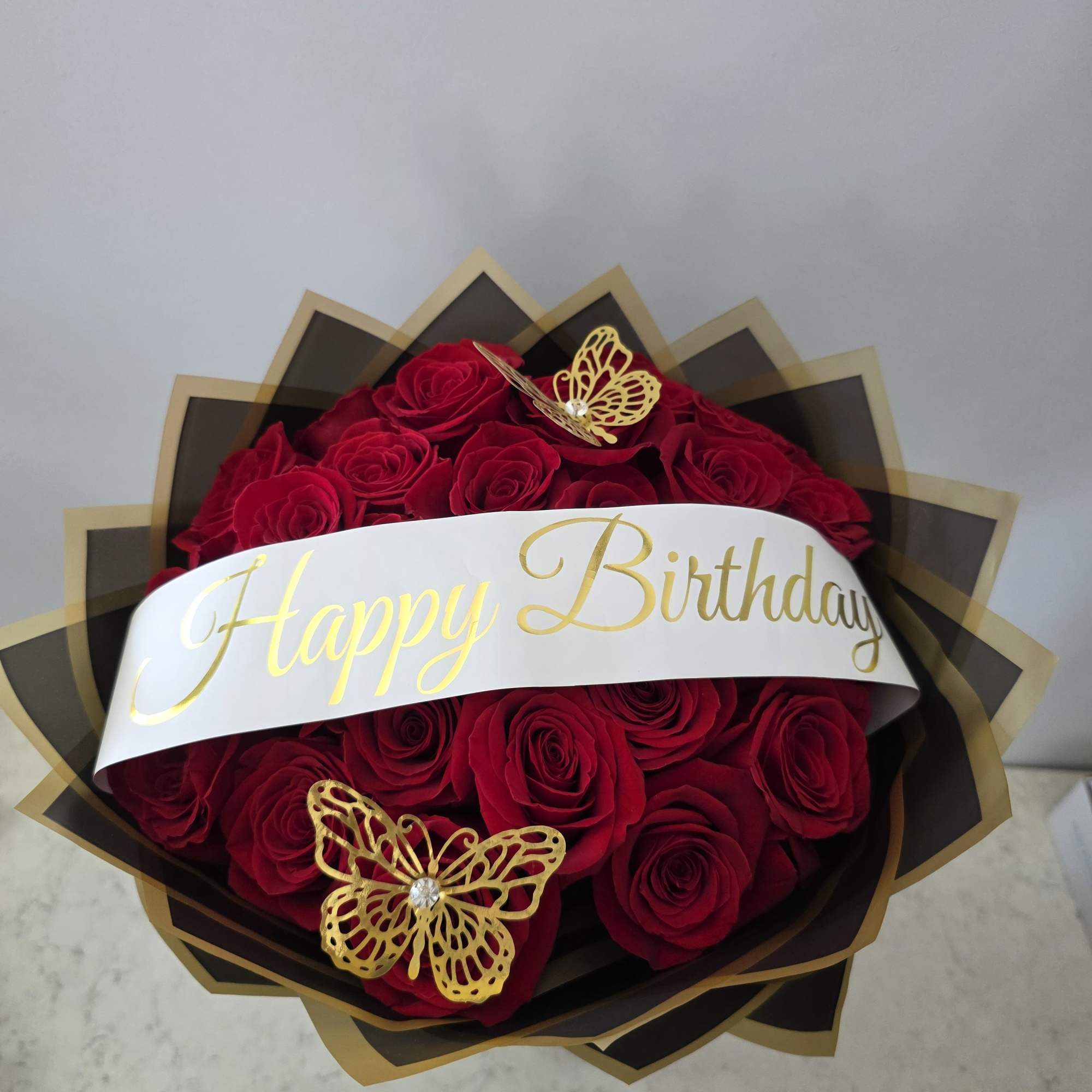 Bouquet of red roses with a Happy Birthday ribbon and gold butterfly accents
