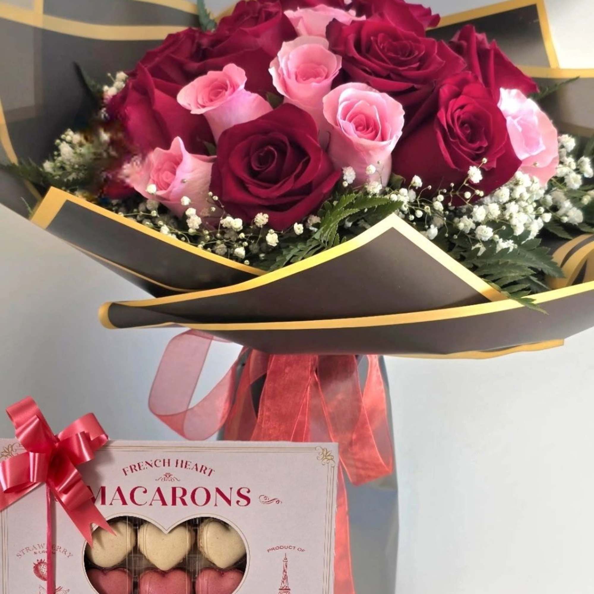 Bouquet of red and pink roses with a box of heart-shaped macarons