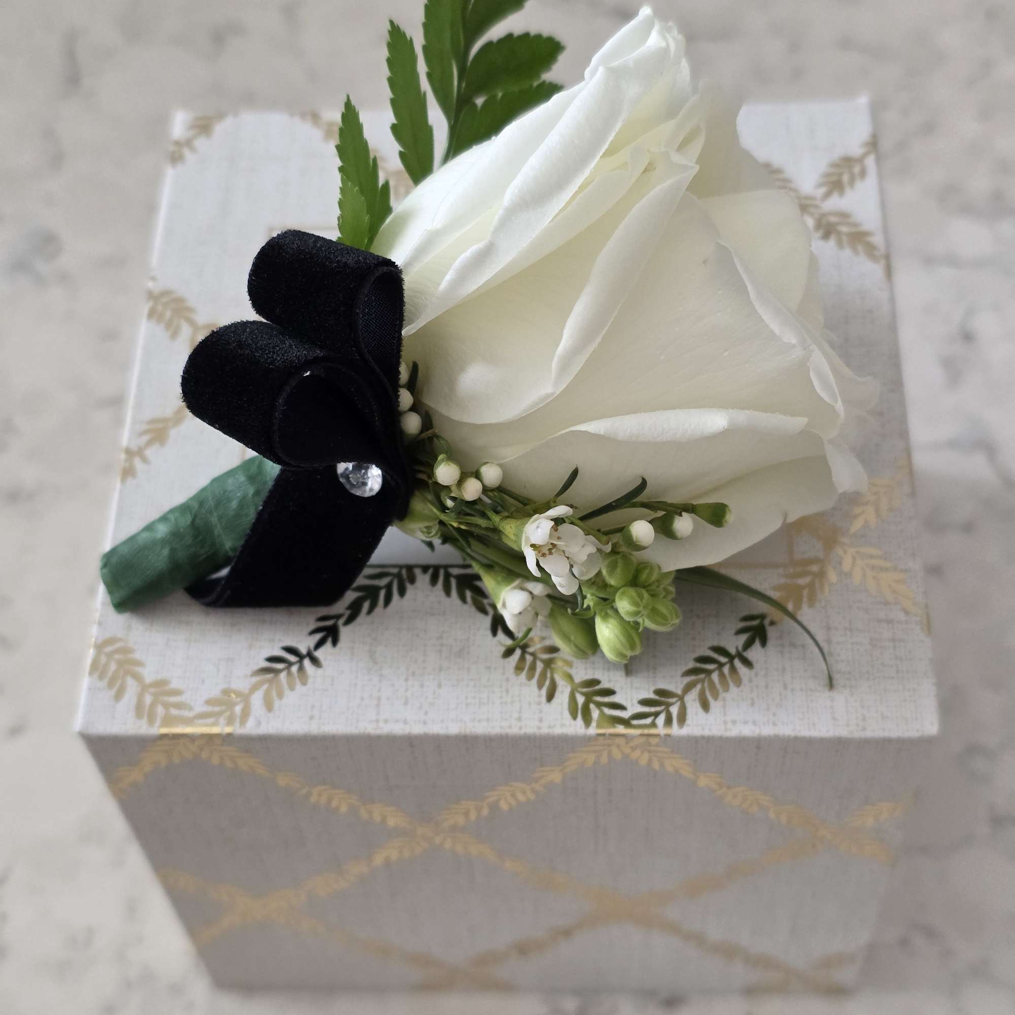 A cluster of pure white roses tied with dark ribbon makes an