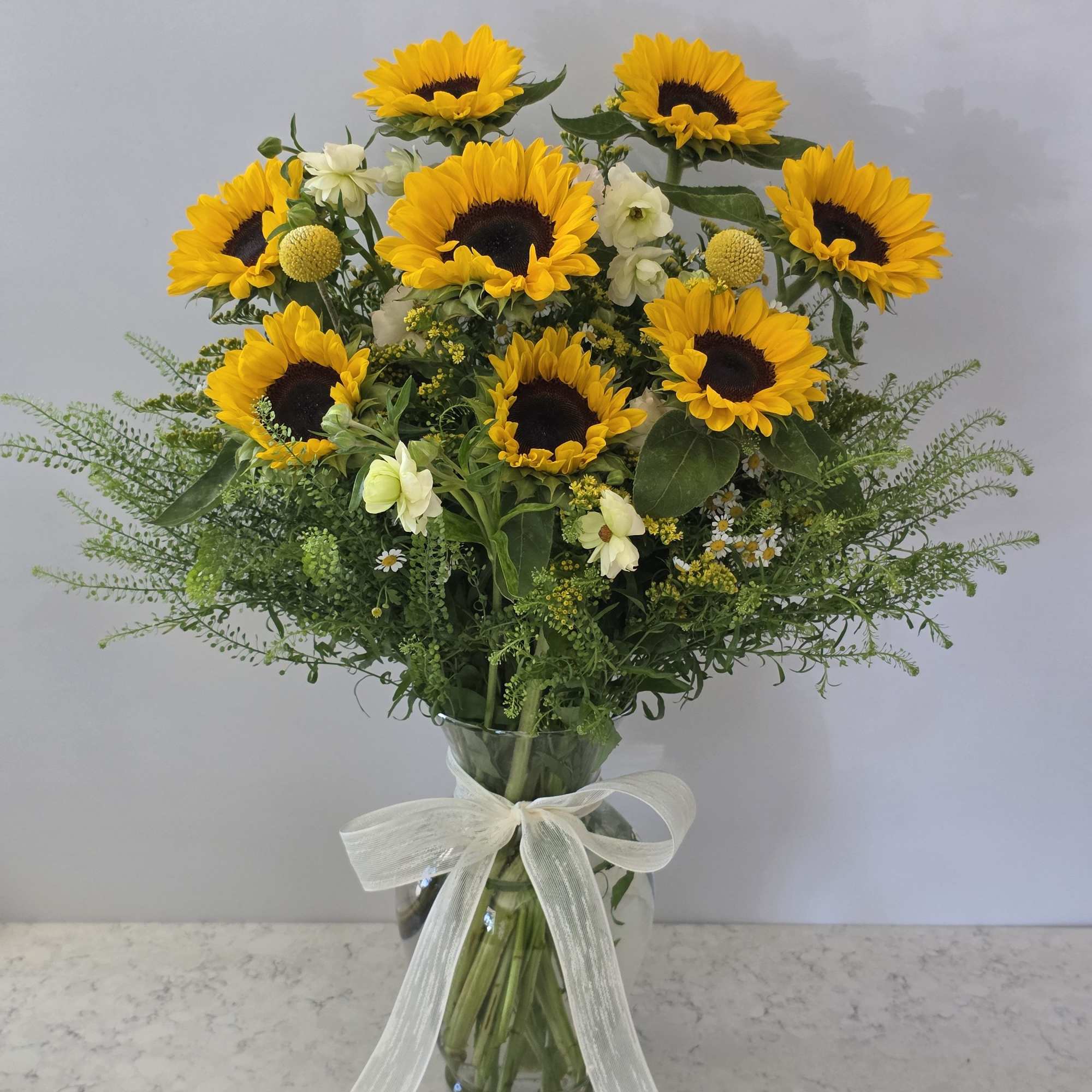 Golden sunflowers steal the show in this vibrant hand-tied flower arrangement, a