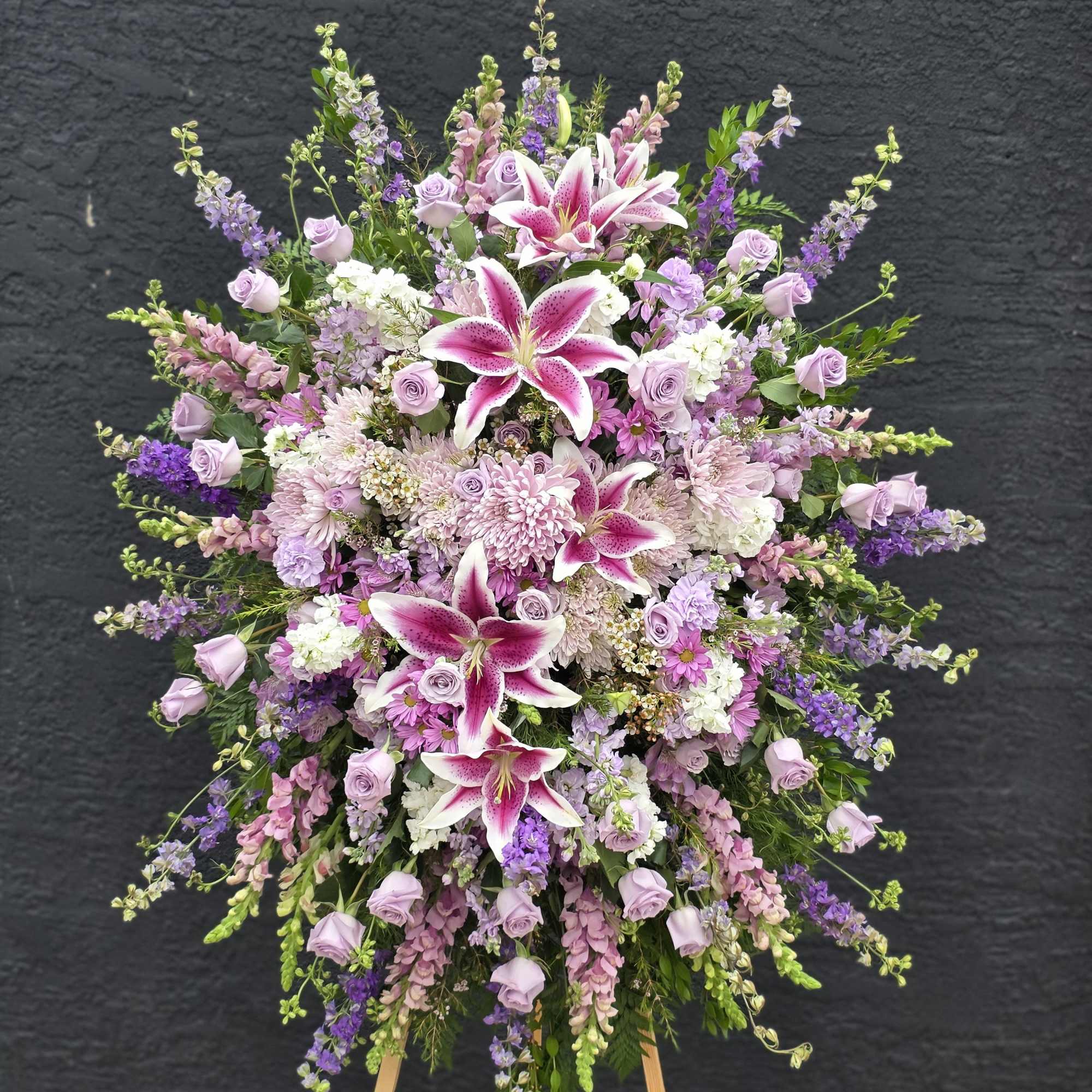 Dense pink lilies and clusters of red and blush roses create the