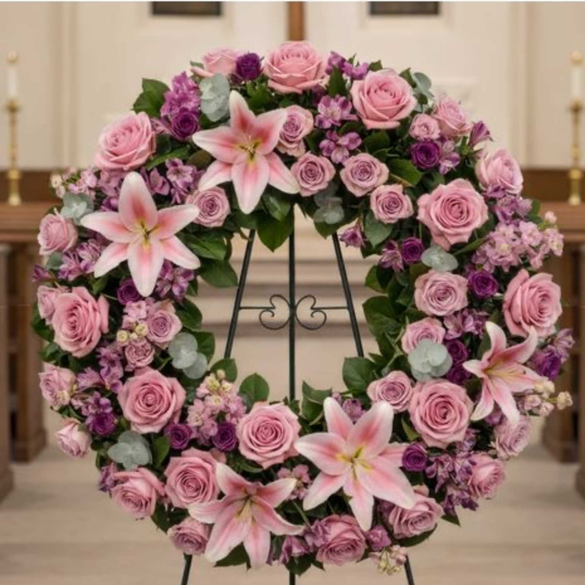 Pink and purple floral wreath on a black stand