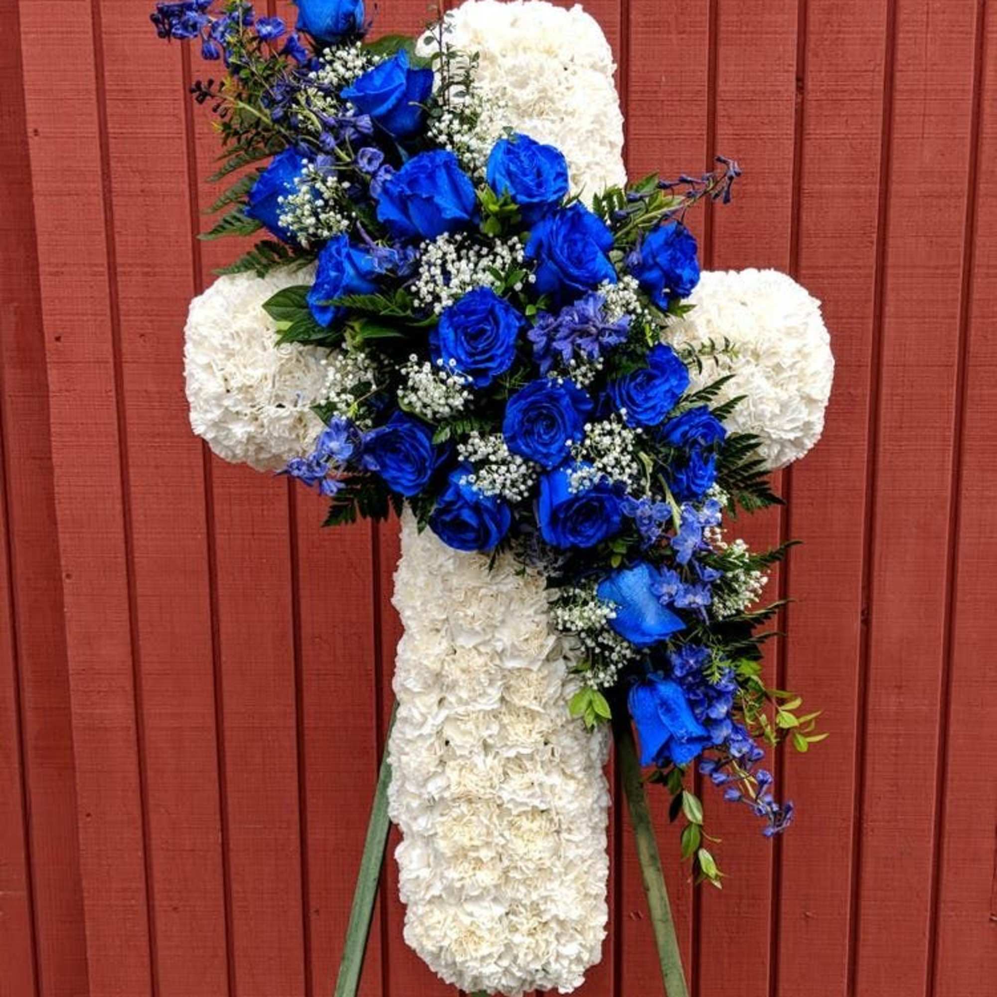 Blue roses and white flowers arranged in a cross on an easel
