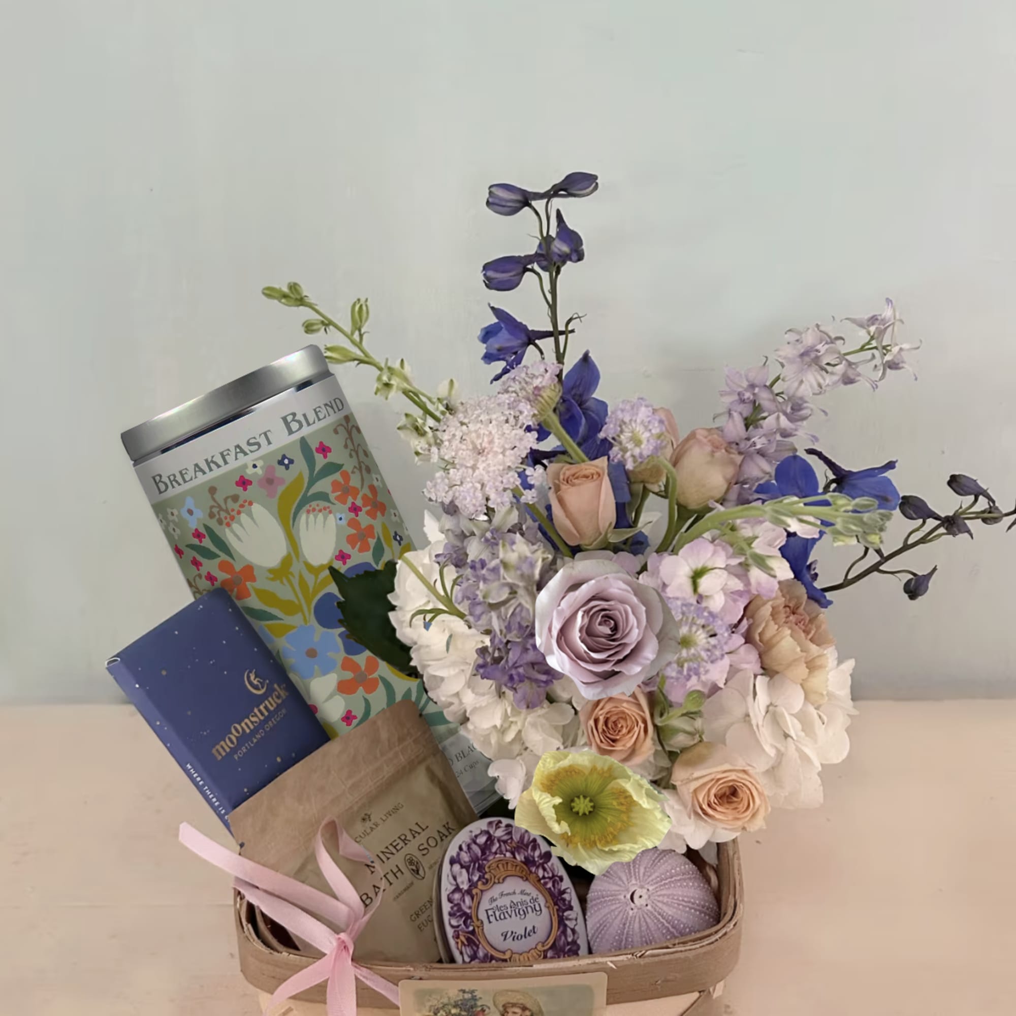 Mixed pastel flower arrangement in a gift basket with bath items