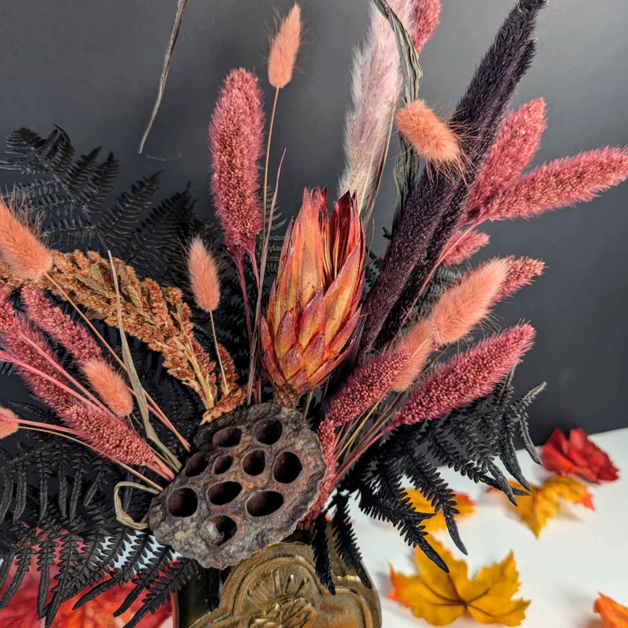 Dried floral arrangement with pink and black grasses in a decorative vase
